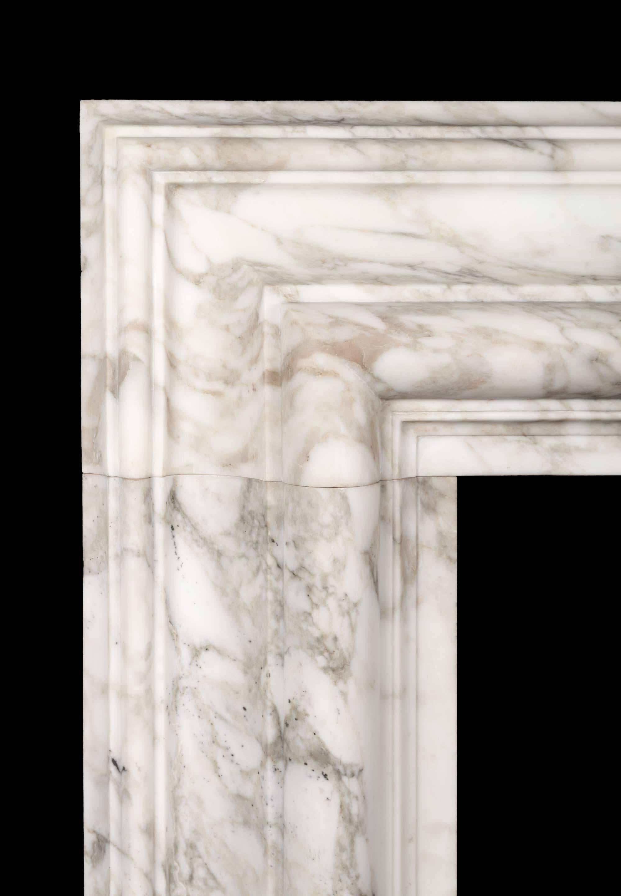 A large bolection fireplace surround of generous proportions . The substantial 12? (300mm) wide bolection moulded frame, rests on plain square plinths.
Carved from a block of beautifully figured, Arabscato Carrara marble, hand selected in Italy by