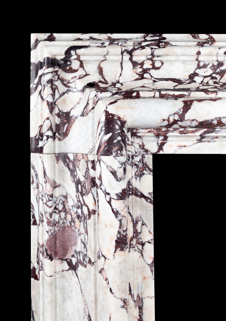A large marble bolection fireplace surround of generous proportions. The substantial 12? (300mm) wide bolection moulded frame, rests on plain square plinths.
Carved from a block of beautifully figured, Breccia viola marble, hand selected in Italy