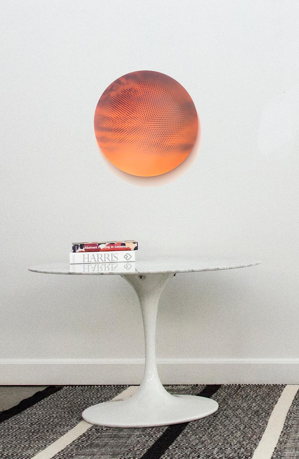 Una stampa a pigmenti in bianco, nero e arancione brillante del sole che sorge tra le nuvole è perforata da un disegno geometrico arancione brillante in questo tondo di Ryan Van Der Hout. Il design preciso e concentrico si illumina di luce arancione