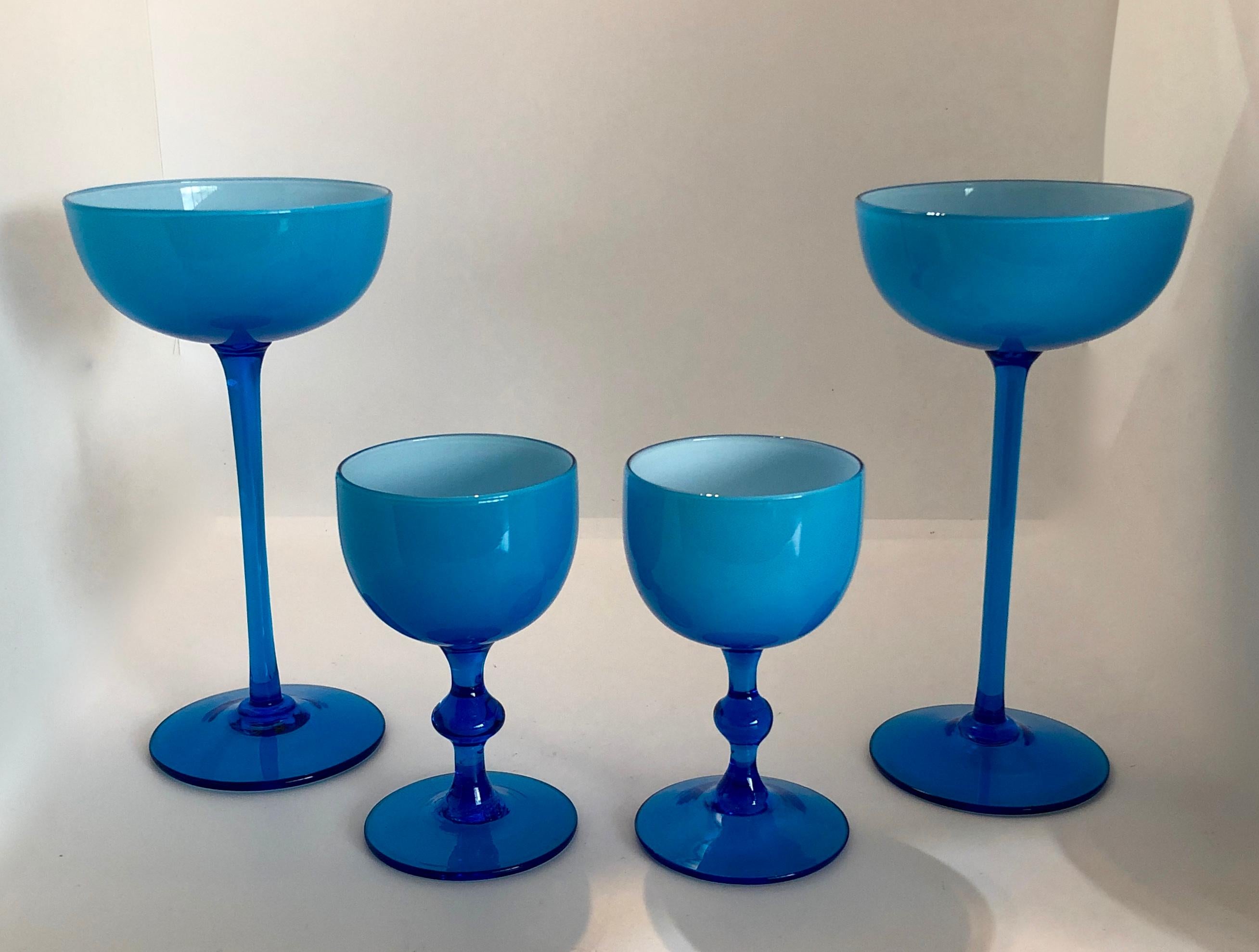 Offered is a Mid-Century Modern set of four Italian blown glass white encased cerulean / light blue stemmed goblets, comprising of two tall stem champagne coupes (measures: 7