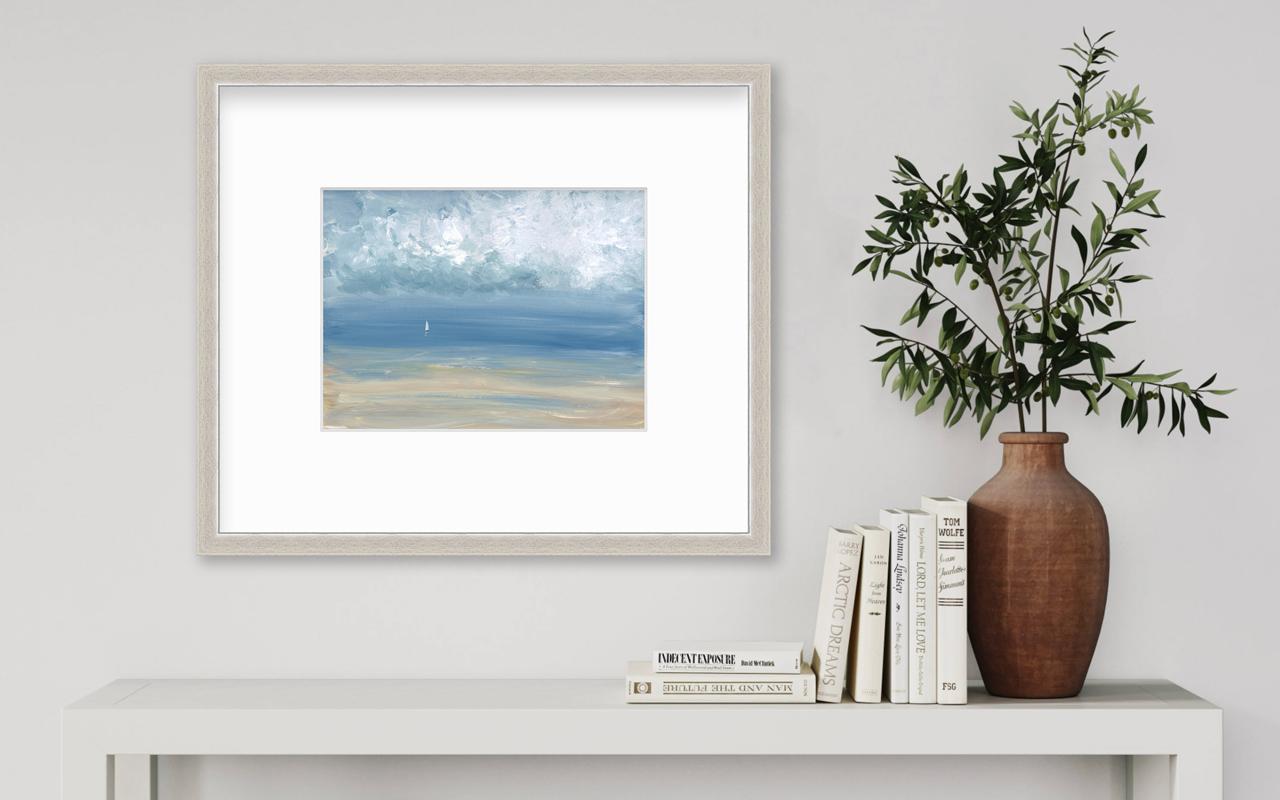 This contemporary seascape limited edition print by S.C. Aldo depicts a loose, abstracted coastal scene with a light blue sky, textured abstract clouds and a small white sailboat sailing near the horizon. A sandy shoreline blends into the water with