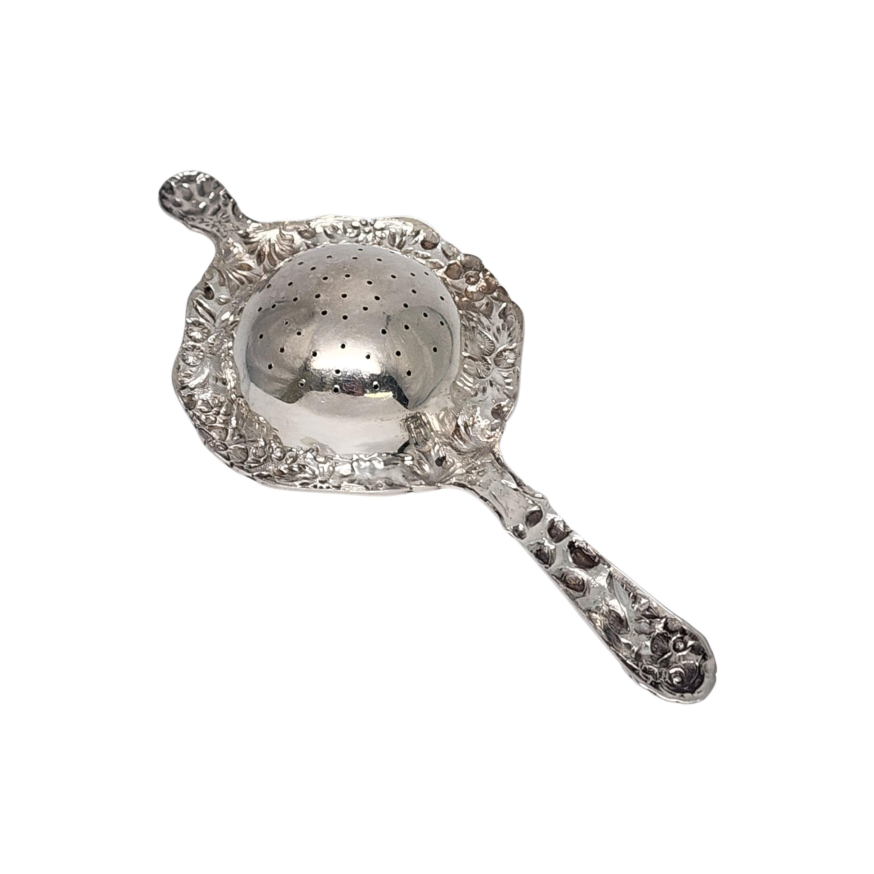S. Kirk & Son sterling silver repousse flower tea strainer.

 No monogram.

This beautifully ornate over the cup tea strainer features an ornate and highly detailed repousse floral design and pierced bowl.

Measures approx 6 1/2