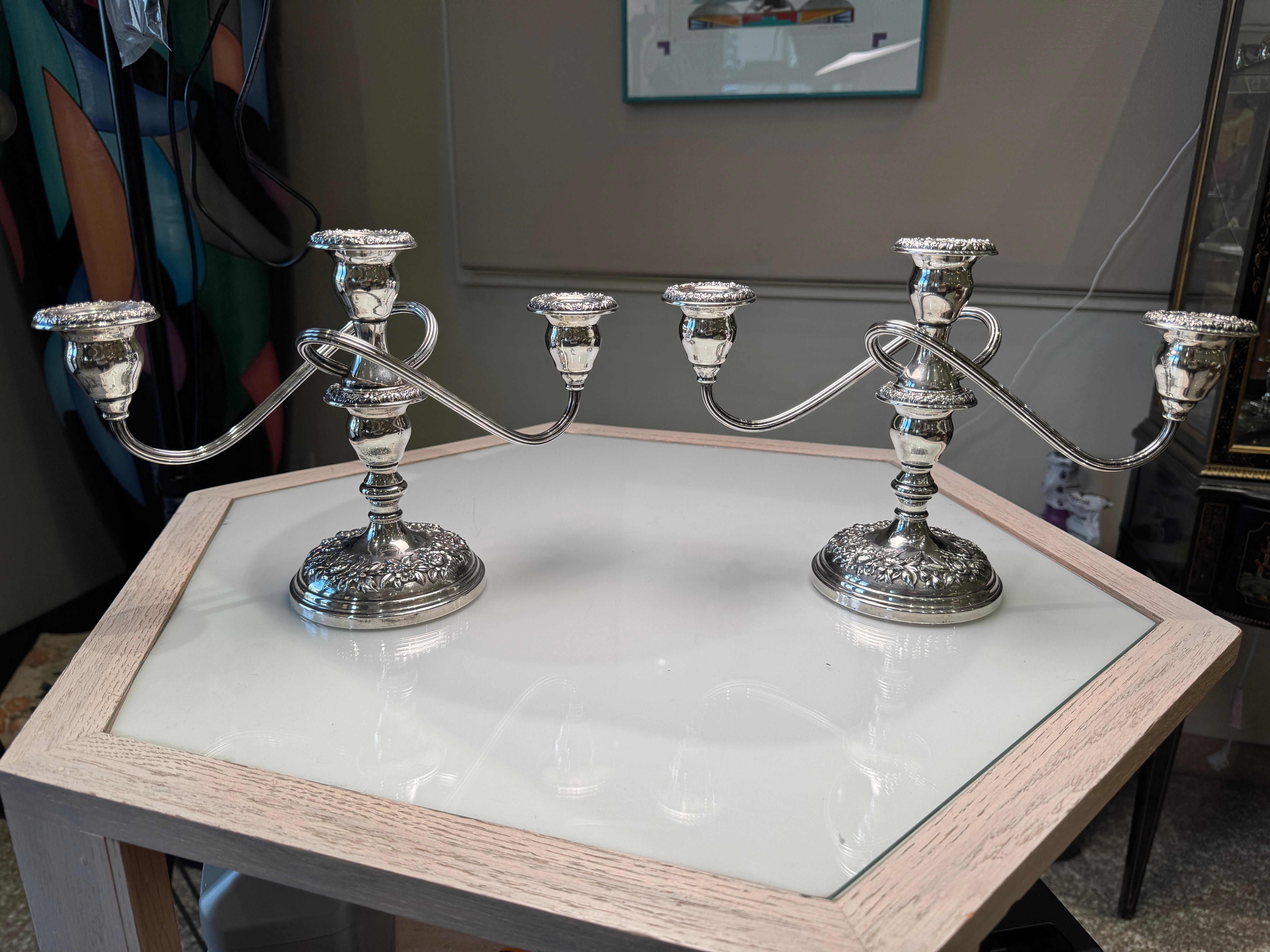 Questa coppia di candelabri in argento sterling di S. Kirk & Son sfoggia il rinomato design repousse di Kirk, caratterizzato da eleganti motivi floreali e a volute sapientemente cesellati a mano dai maestri argentieri. Realizzati negli Stati Uniti,