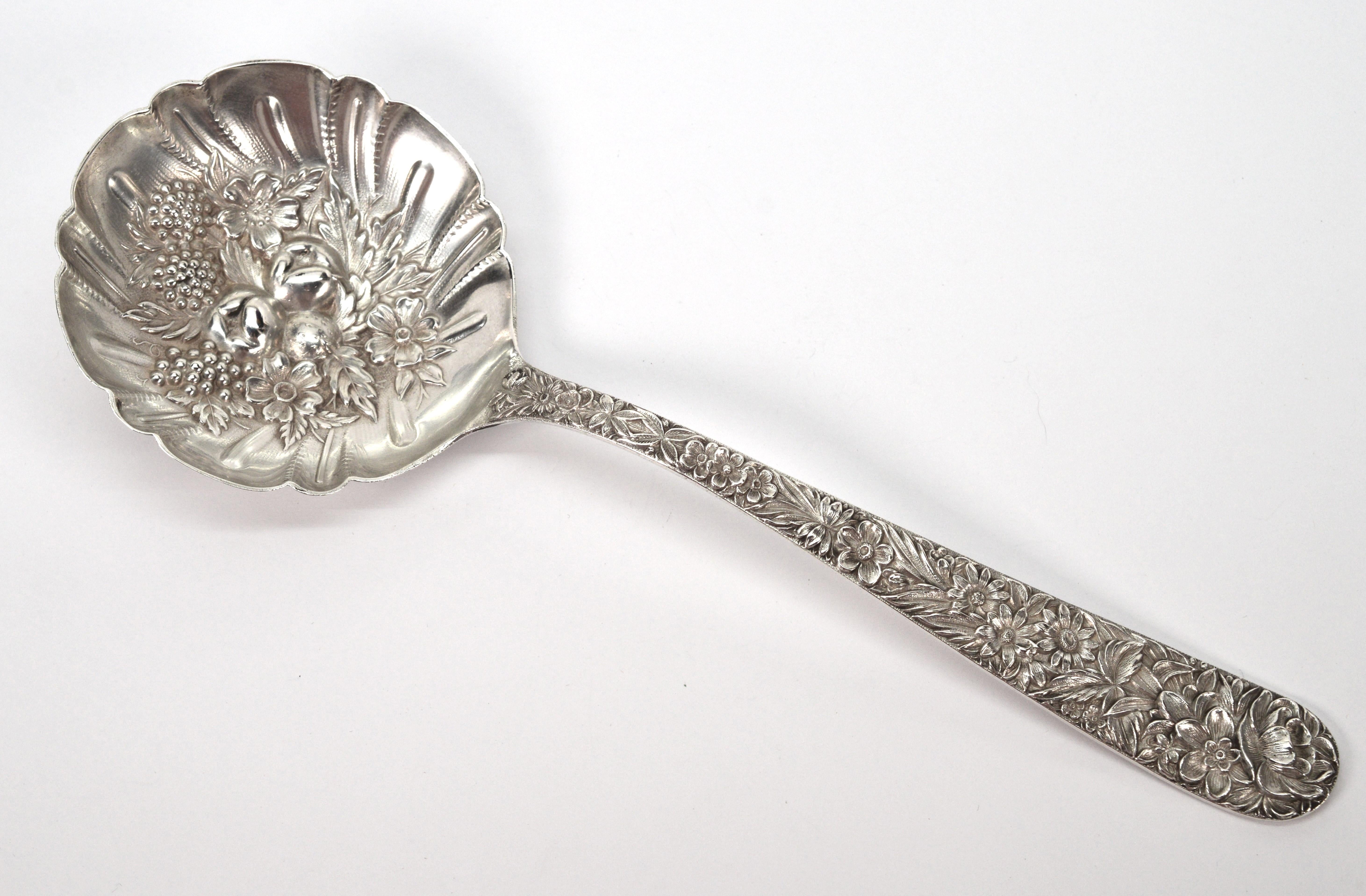 By S. Kirk & Sons, circa 1930, add this artful repousse sterling silver fruit compote serving spoon to your fine tableware collection. In excellent condition and polished, this lovely nine inch long sterling silver serving spoon has a three inch