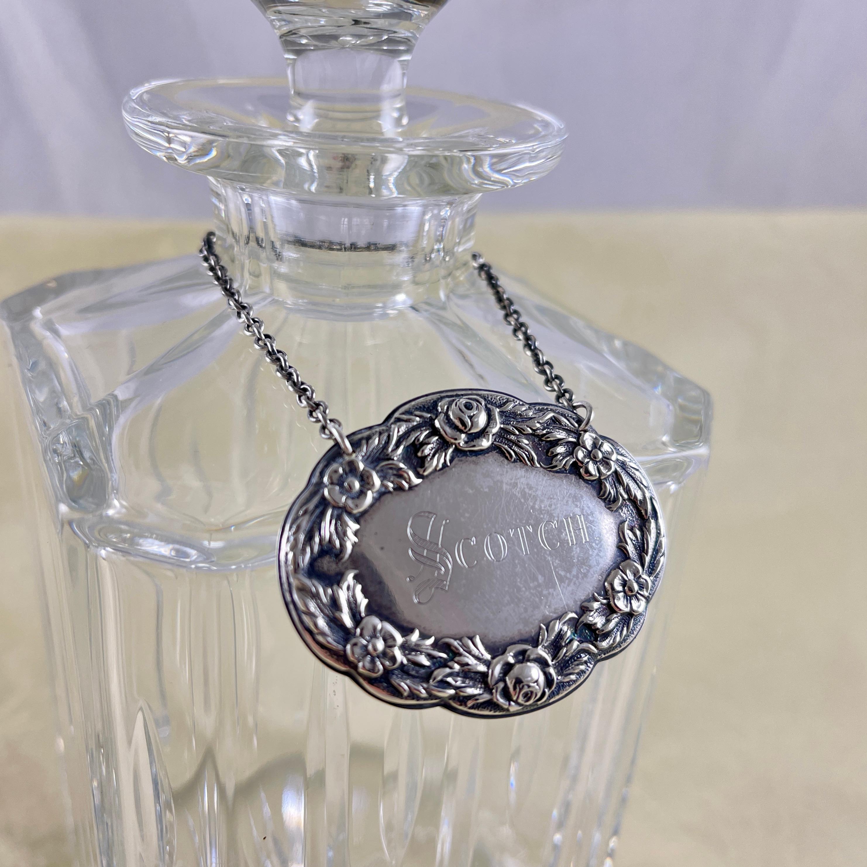 From the S. Kirk & Sons Silver Company in Baltimore, Maryland, a sterling silver liquor collar tag, circa 1860s.

The oval tag has a Repousse Rose and floral garland border, and is engraved, Scotch, in a light double block type. It hangs from a