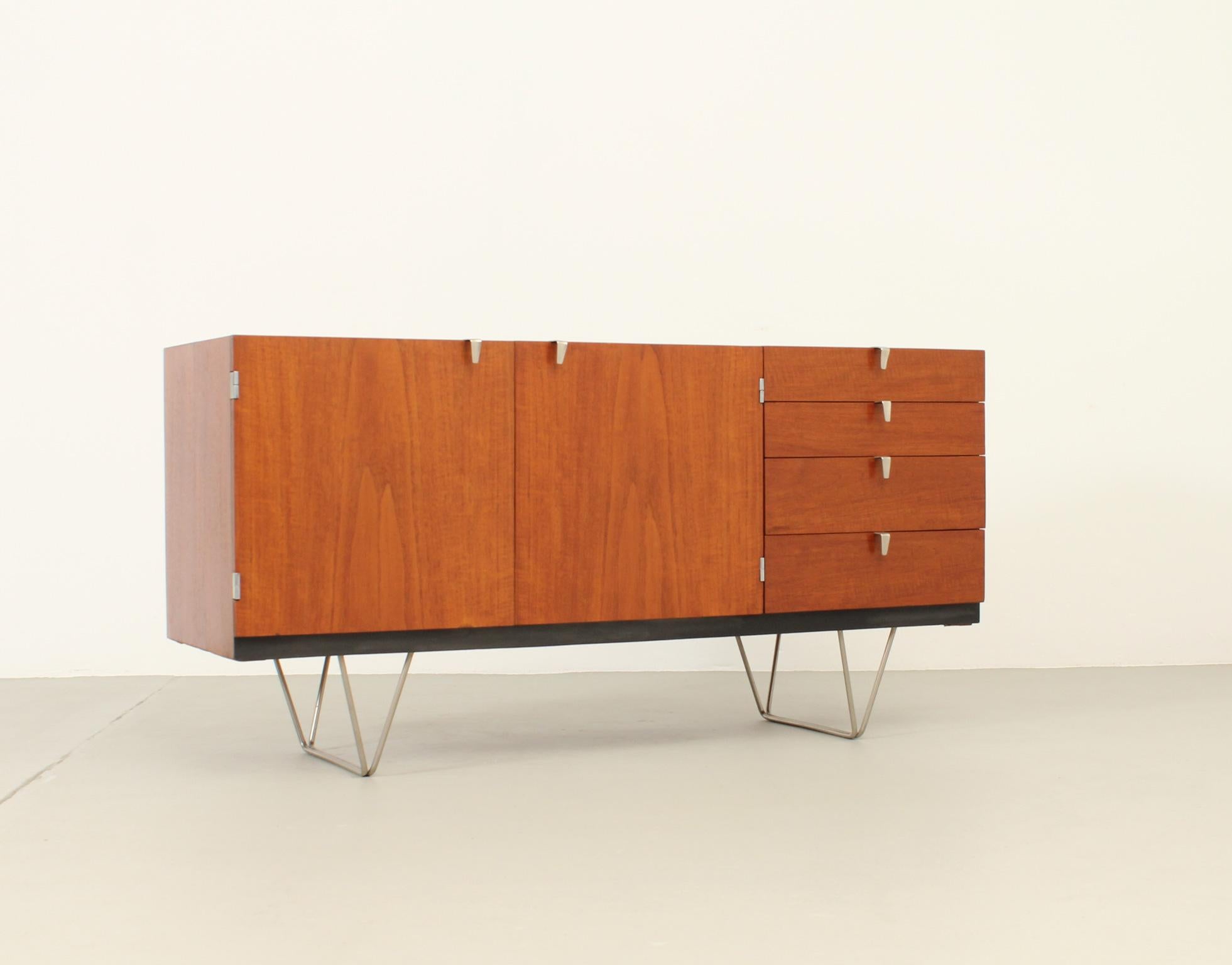 S Range sideboard designed in 1959 by John and Sylvia Reid for Stag Furniture, UK. An icon post-war british design. Teak wood with beech interior and polished steel bases and handles. Two doors and four drawers with two pull out trays inside. Signed