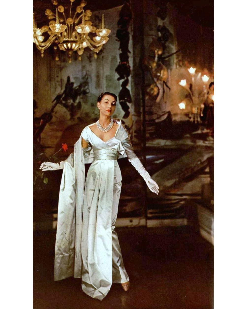 S/S 1955 Christian Dior (Attributed) short sleeve ecru satin gown with sash. Short sleeve gown with pleated bust and raised pleated detail to side, with sash that drapes over shoulder, and additional sash detail draping from waist to hem. Back zip