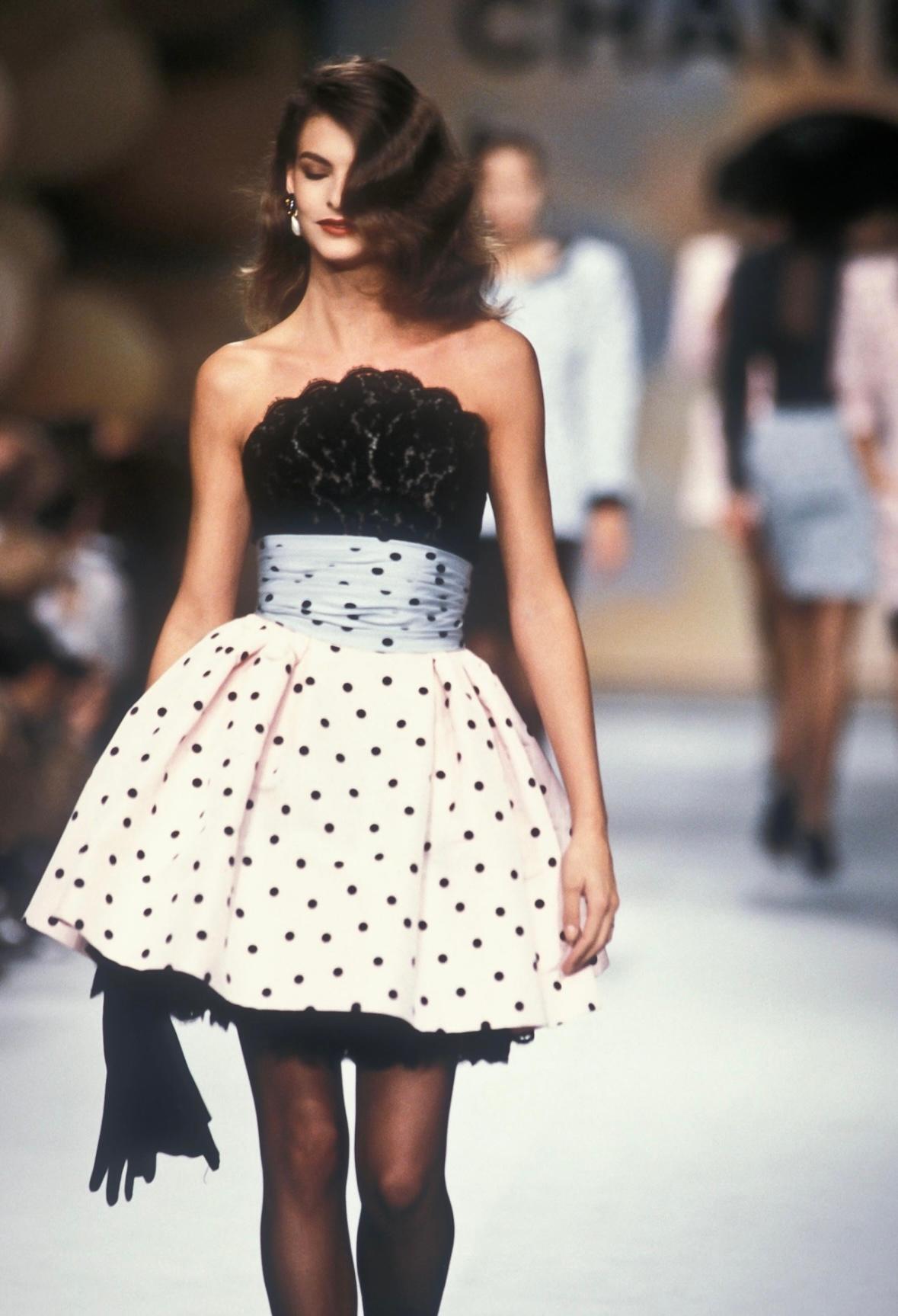 Linda Evangelista modeled the pastel version of this feminine Lagerfeld-designed Chanel dress on the Spring/Summer 1988 runway. This fabulous black strapless mini dress is covered in lace and white polka dots. This short dress features a