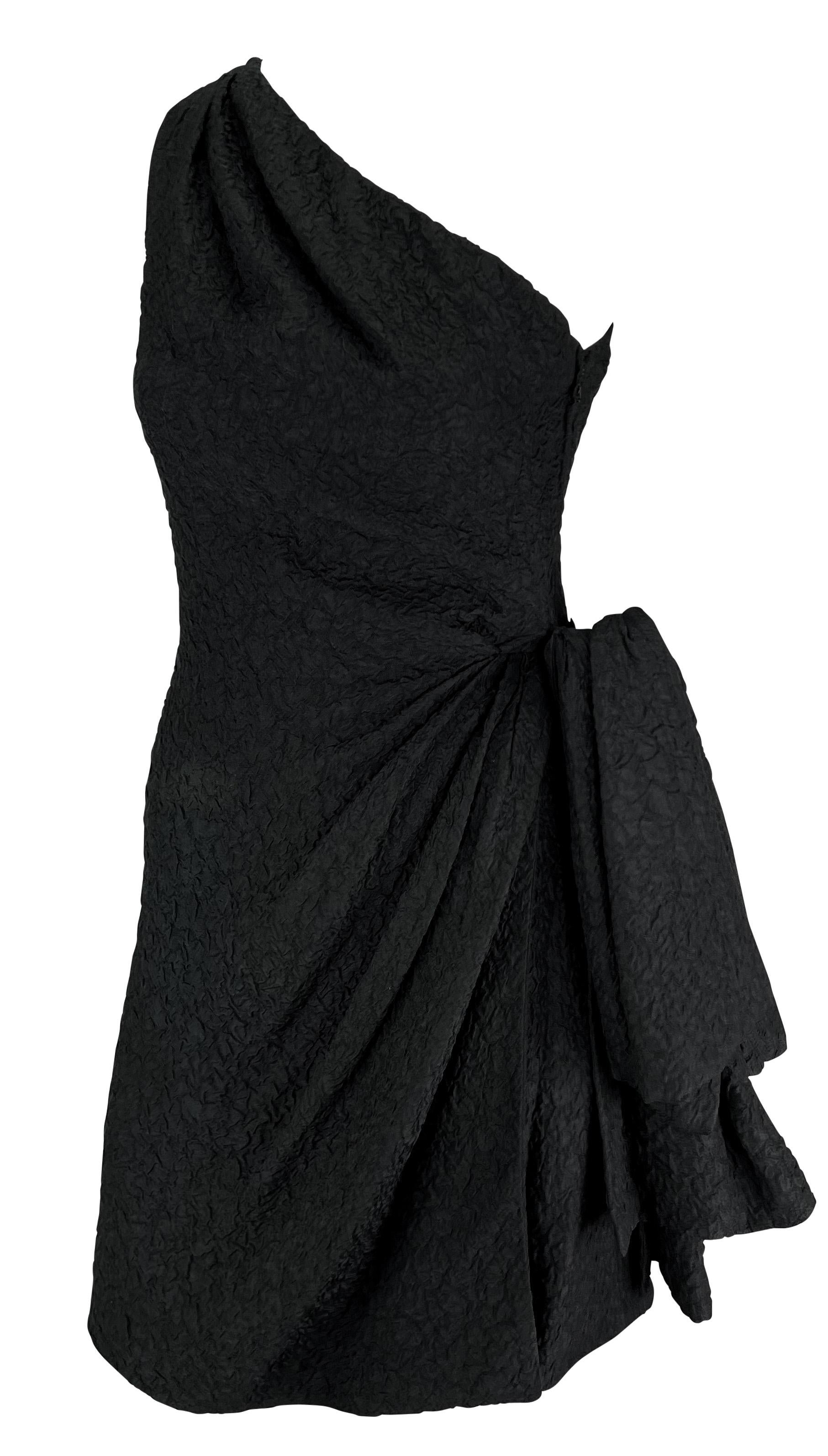 This chic black textured Yves Saint Laurent single-shoulder mini dress from the Spring/Summer 1988 collection is crafted entirely from beautifully textured silk. It features ruching at the single shoulder strap and opposite hip, along with a slit
