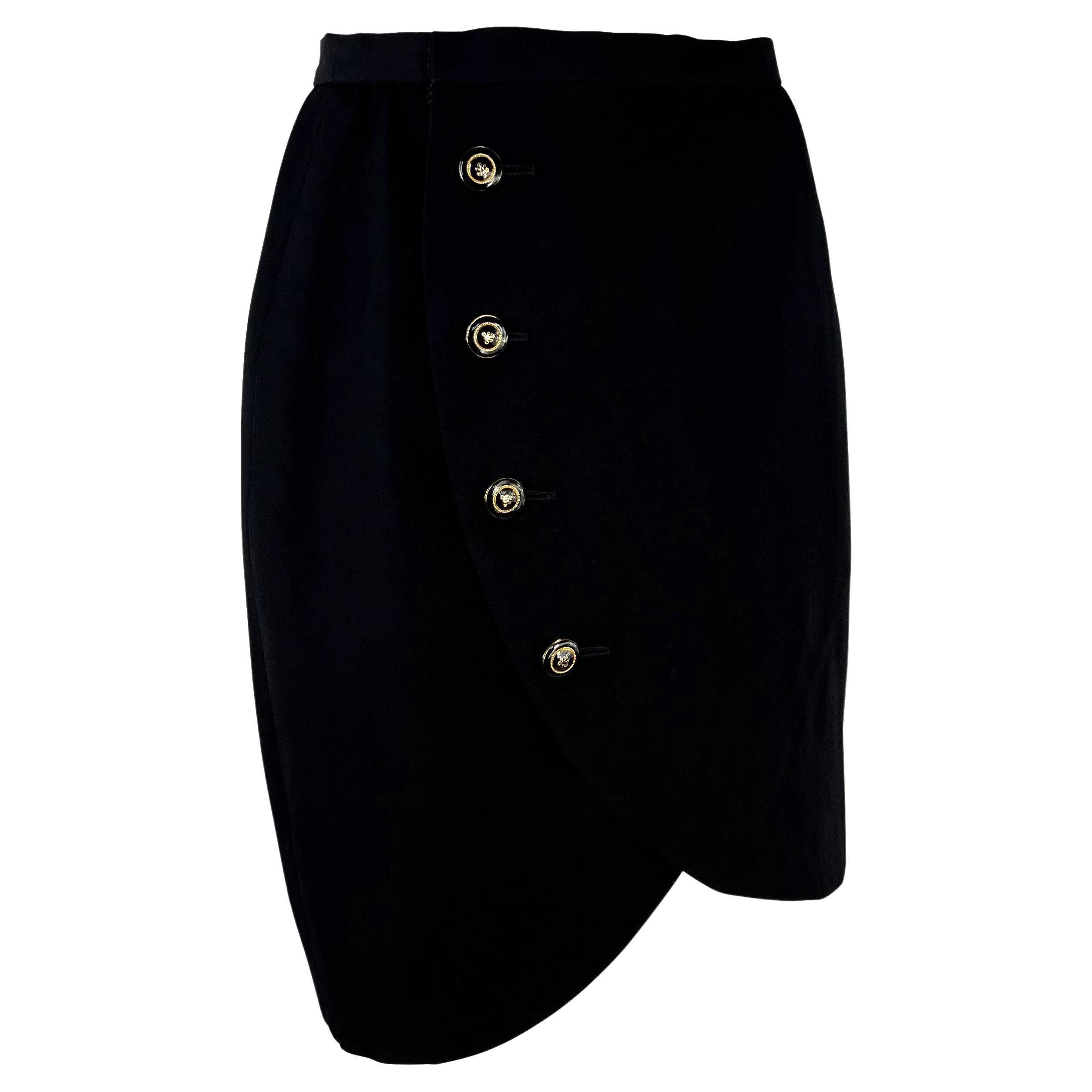 Presenting a black wrap Yves Saint Laurent Rive Gauche skirt, designed by Yves Saint Laurent. From the Spring/Summer 1989, this timeless skirt features a curved cut hem and is made complete with gold-tone and black enamel buttons. 

Approximate