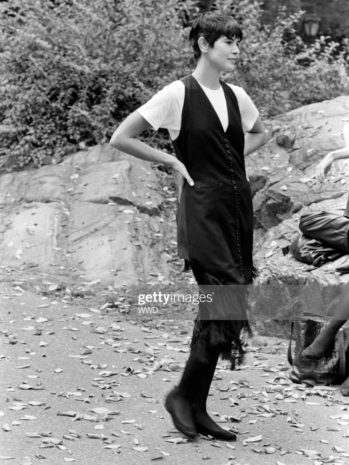 Presenting a fabulous black Norma Kamali button-down mini dress. First presented in the Spring/Summer 1990 runway, this vest-style dress boasts a plunging v-neckline, faux hip pockets, and a tie-back feature. Chic and tastefully provocative, this