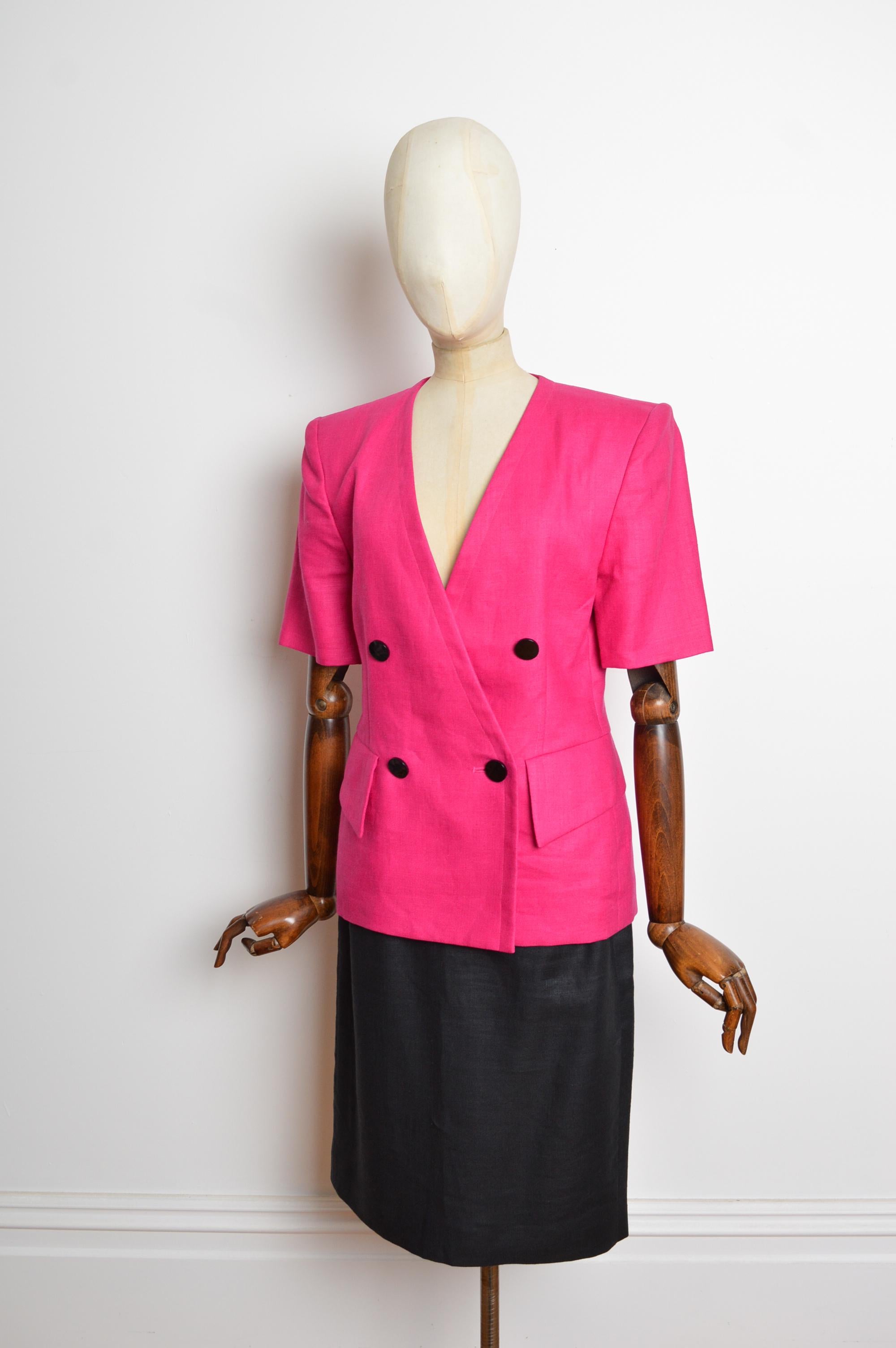 Un abito di lino rosa shocking di Yves Saint Laurent, della collezione primavera/estate 1990. Caratterizzato da una giacca boxy a maniche corte e doppiopetto con gonna in lino lunga fino al ginocchio. 
Le misure sono indicate in pollici ('')
Taglia