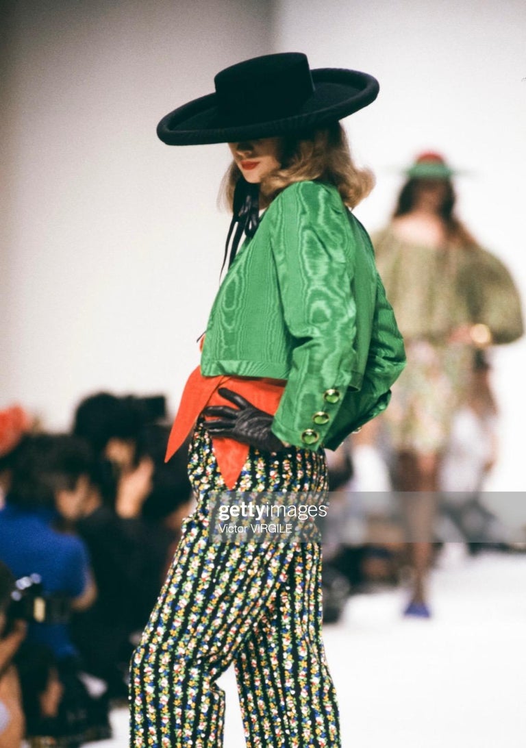 TheRealList presents: a bright blue cropped jacket designed by Yves Saint Laurent for his Spring/Summer 1990 collection. Each cuff is accented with three large Gripoix glass faux buttons that shine brilliantly against the moire silk sleeves. A green