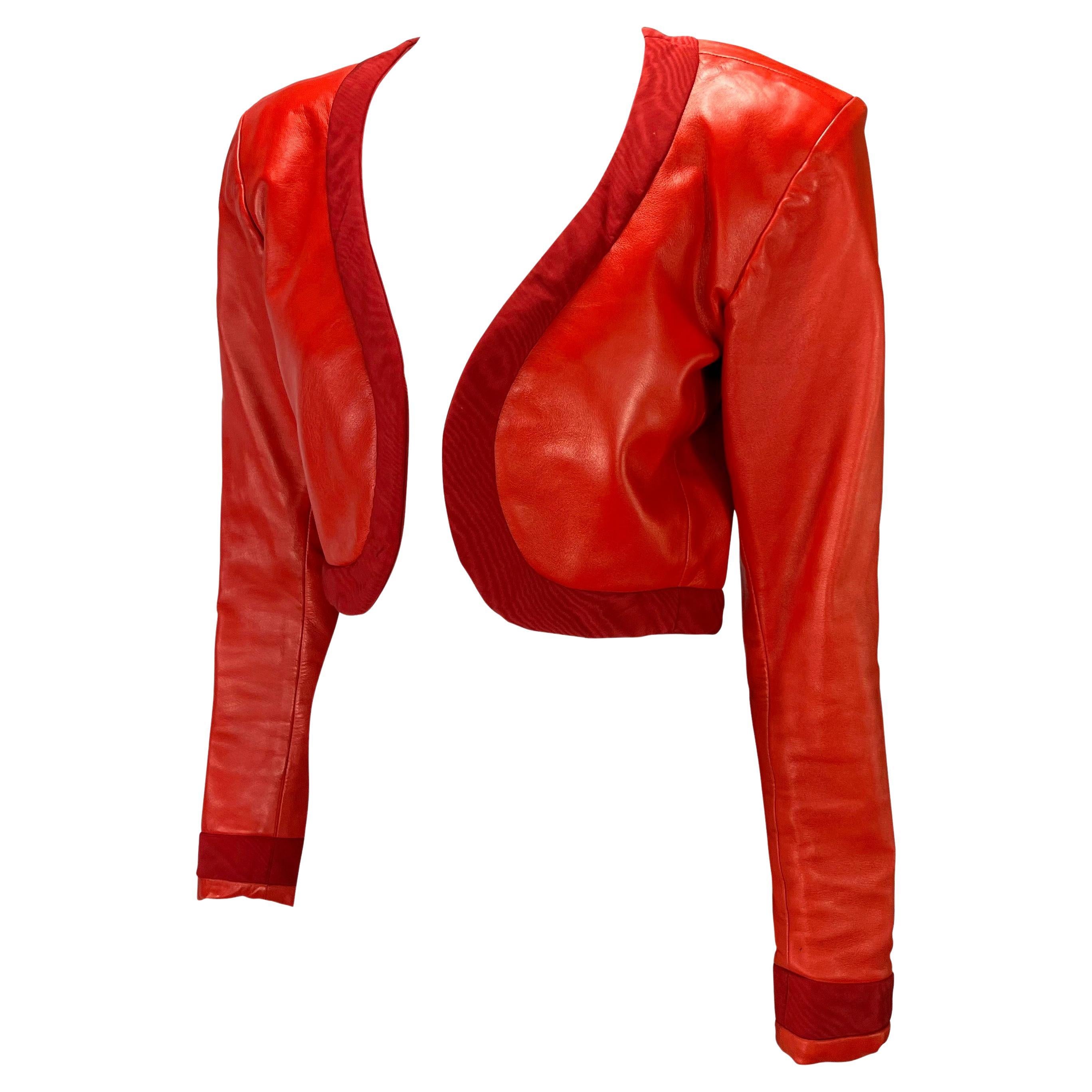 Présentation d'une veste en cuir rouge vif Yves Saint Laurent Rive Gauche, créée par Yves Saint Laurent. Issu de la collection printemps-été 1990, ce fabuleux boléro est presque entièrement en cuir et est complété par une large bordure autour du