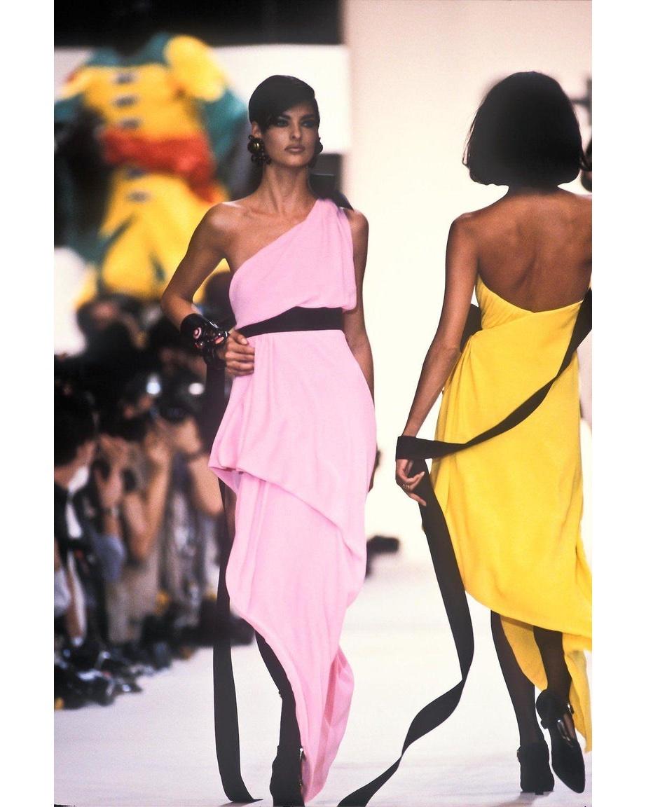 S/S 1991 Chanel one-shoulder pink gown with black silk ribbon accents around waist and bow at shoulder. Beautiful Grecian-style gown with subtle drape and fitted waist. As seen on the runway on Linda Evangelista and featured in the ad campaign worn