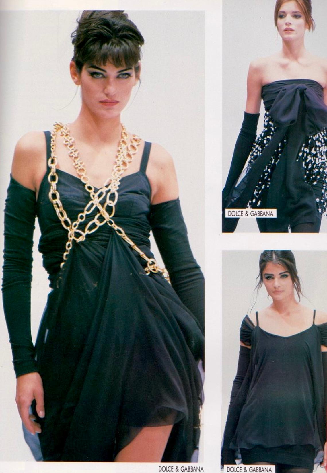 Ich präsentiere ein fabelhaftes schwarzes Bodycon-Minikleid von Dolce & Gabbana. Dieses Kleid aus der Kollektion Frühjahr/Sommer 1991 ist mit goldfarbenen Kettenträgern und einem Rundhalsausschnitt verziert. Ähnliche Kettendetails waren auf dem