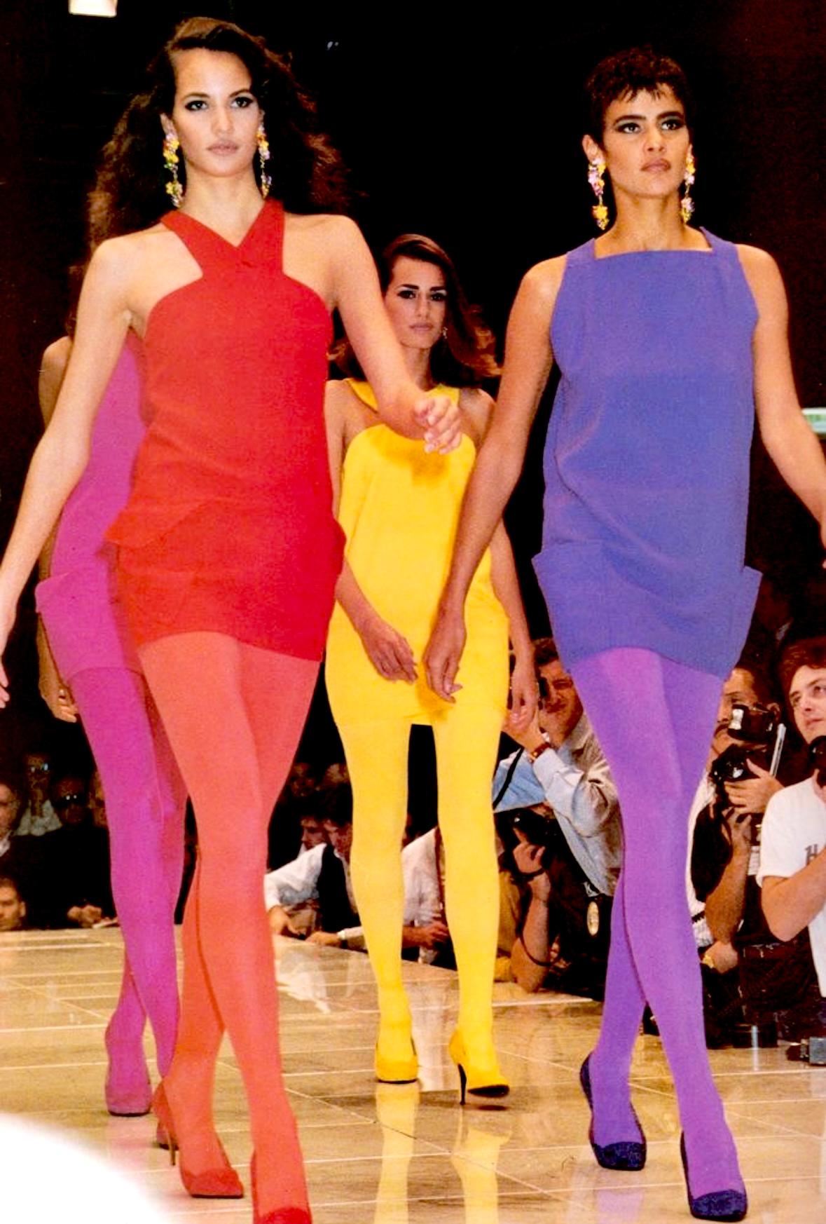 Présentation d'une mini robe rouge vif Gianni Versace, créée par Gianni Versace. Issue de la collection printemps/été 1991, cette robe a fait ses débuts sur le podium de la saison et est apparue dans la campagne publicitaire de la saison,