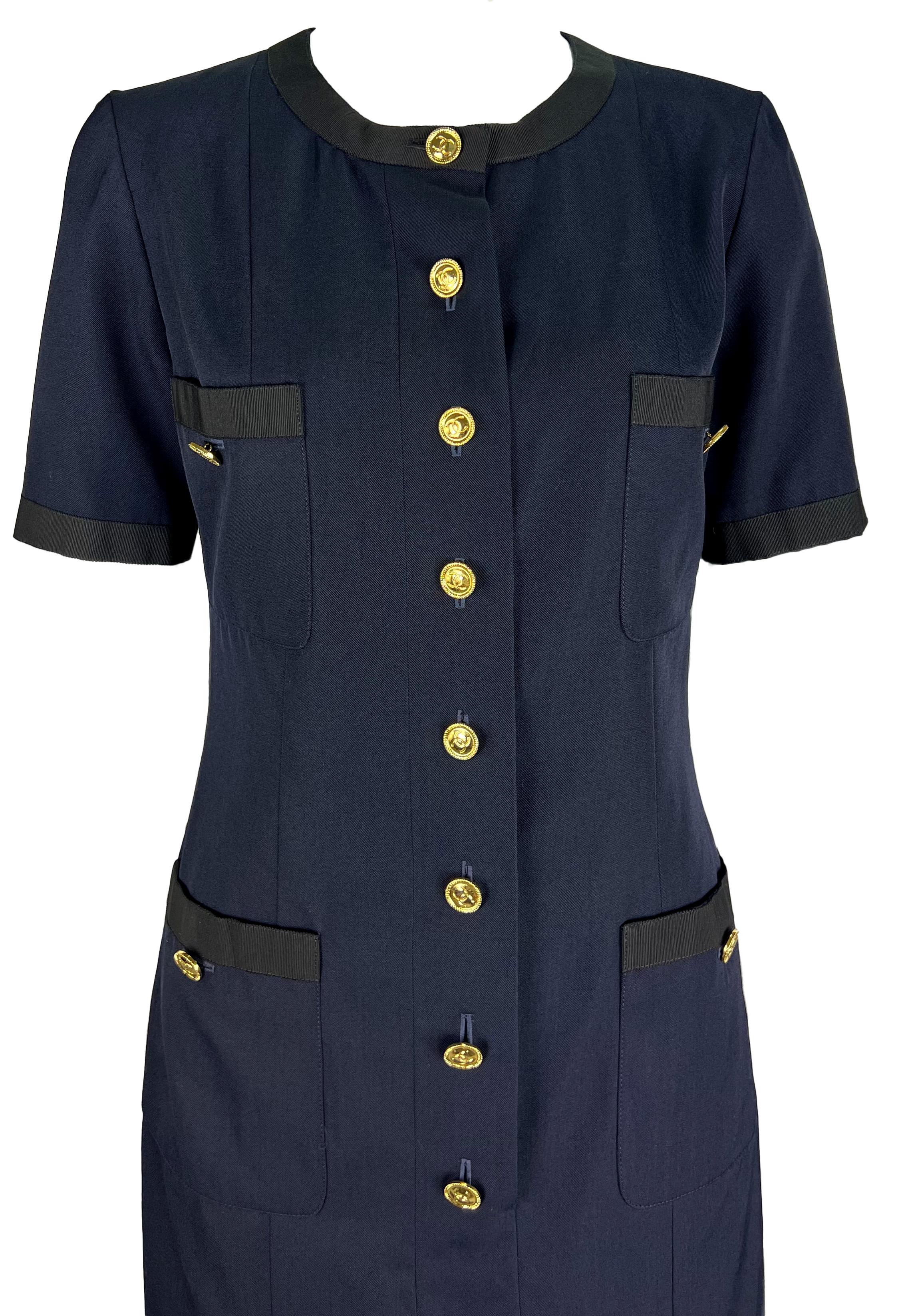 Karl Lagerfeld a dessiné cette fabuleuse robe chemise bleu marine de Chanel pour la collection printemps/été 1992. Il présente des détails noirs sur les poches, l'encolure et les bras. La robe est complétée par des boutons dorés de la marque Chanel