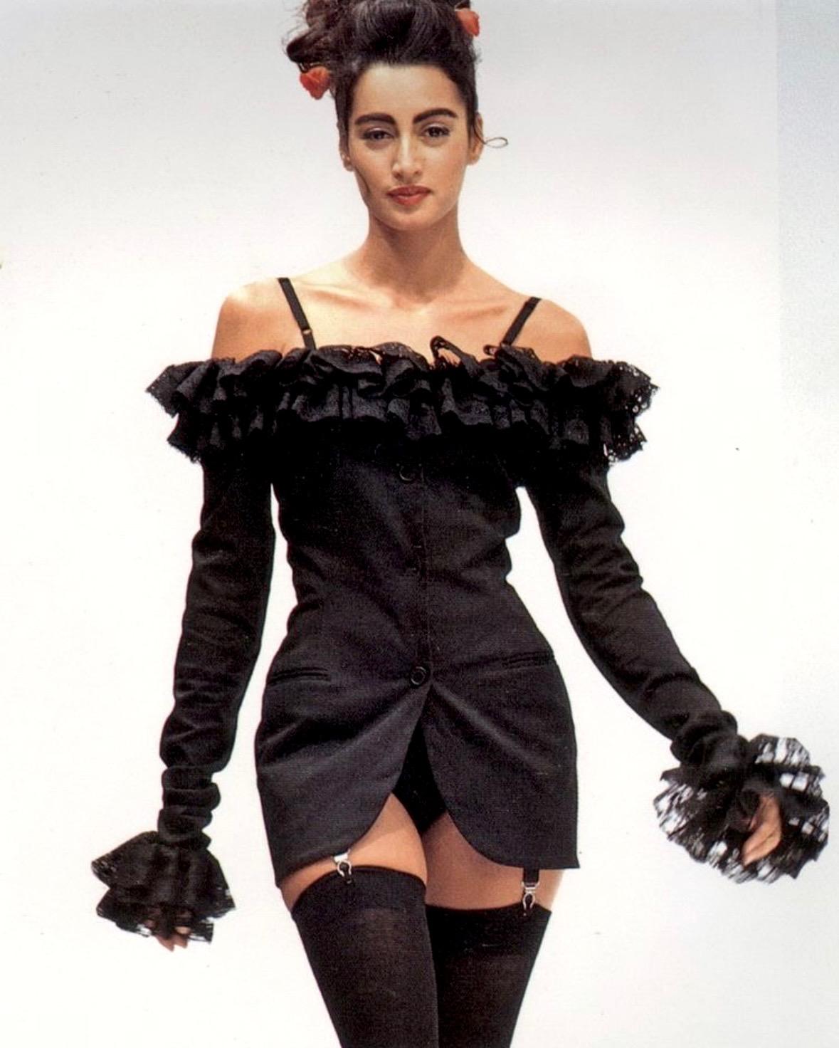 Presenting a fabulous black ruffle Dolce and Gabbana crop stop. From the Spring/Summer 1992 collection, this top features a tie between the breasts and lightly flared long sleeves. The top hangs from small straps that allow the top to hang off the