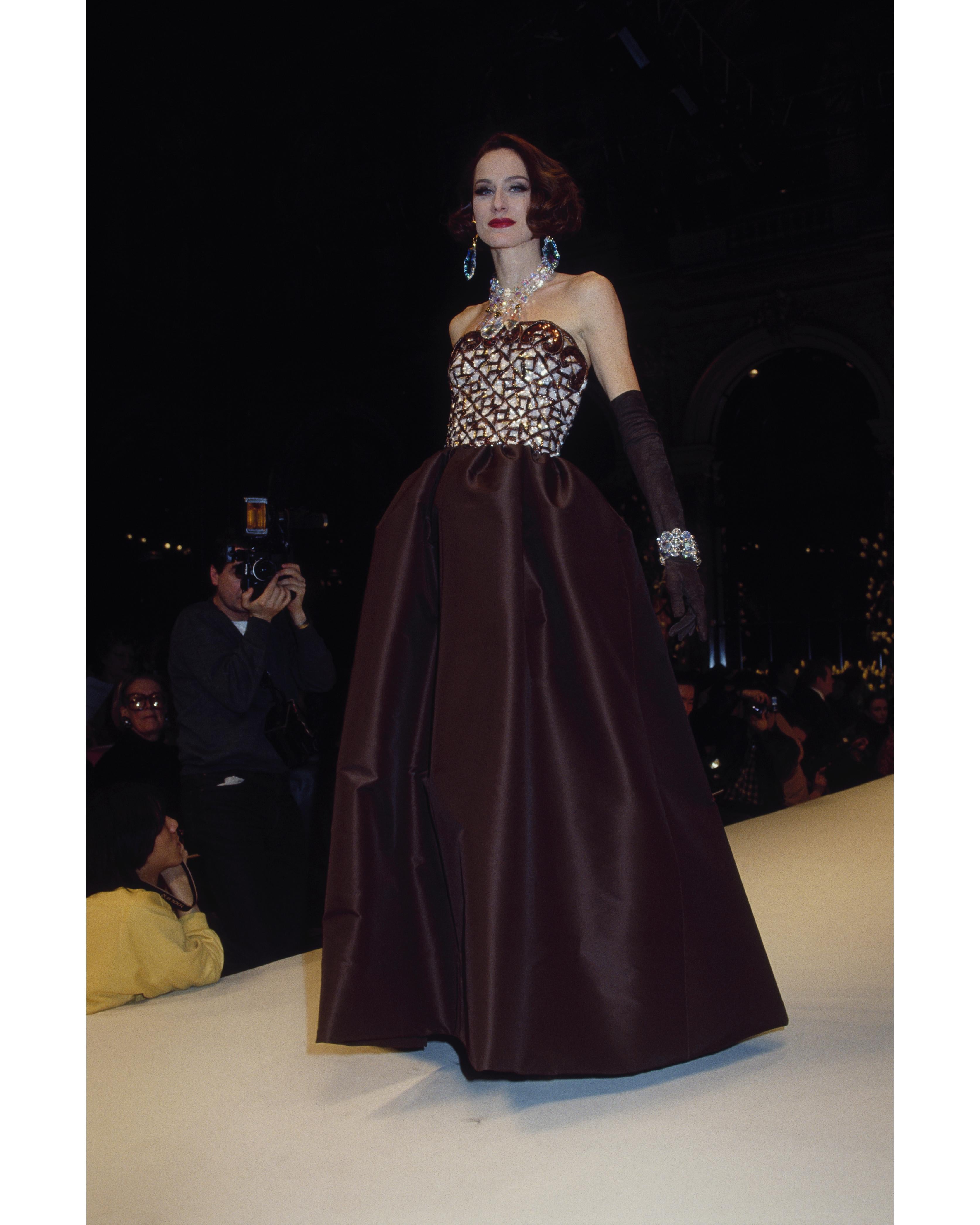 S/S 1992 Givenchy Haute Couture deep brown strapless gown with embroidered sequin and raffia bustier by Maison Lesage. Bustier features brown geometric pattern throughout and 3D filigree curved loop details at top. Side zip closure and functional