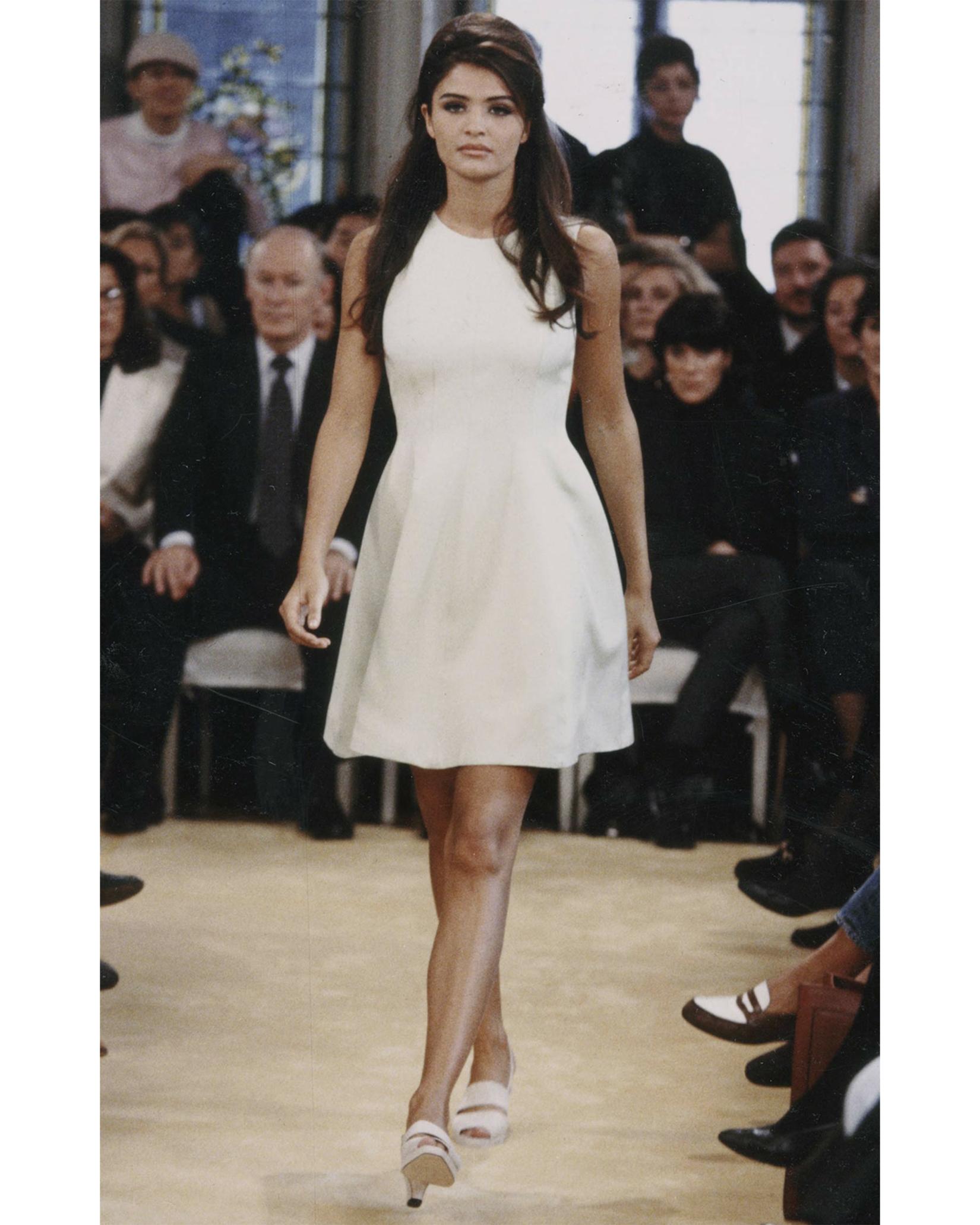 S/S 1992 Prada by Miuccia Prada muted beige scoop neck sleeveless mini dress. Trumpet silhouette with fitted waist and full skirt. Features visible curved seams at upper to create flattering silhouette at waist. Concealed back zip closure with tan