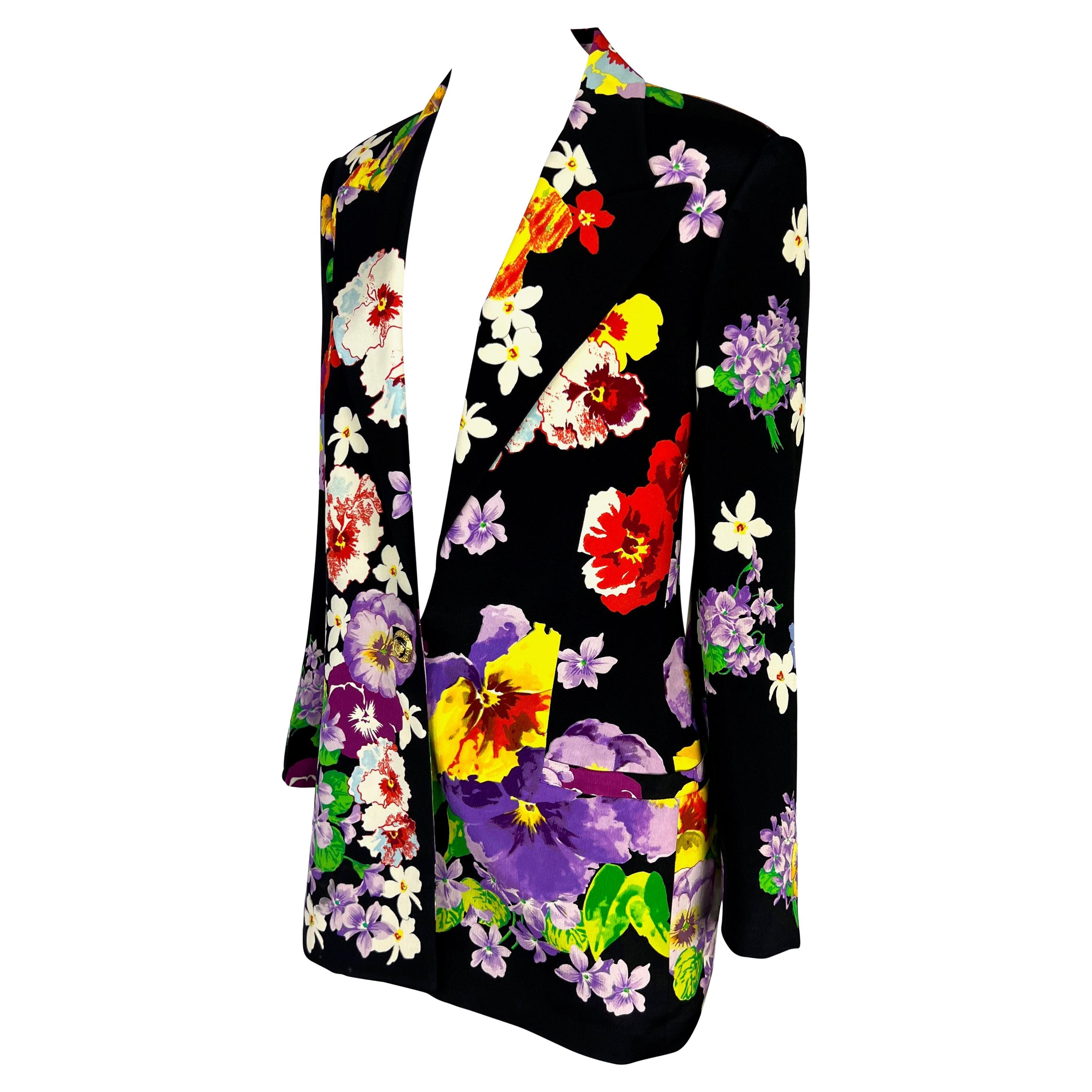 Presenting a beautiful multicolored floral Gianni Versace blazer, designed by Gianni Versace. From the Spring/Summer 1994 collection, this gorgeous blazer features a black background with a vibrant multicolor floral print on top. The added length