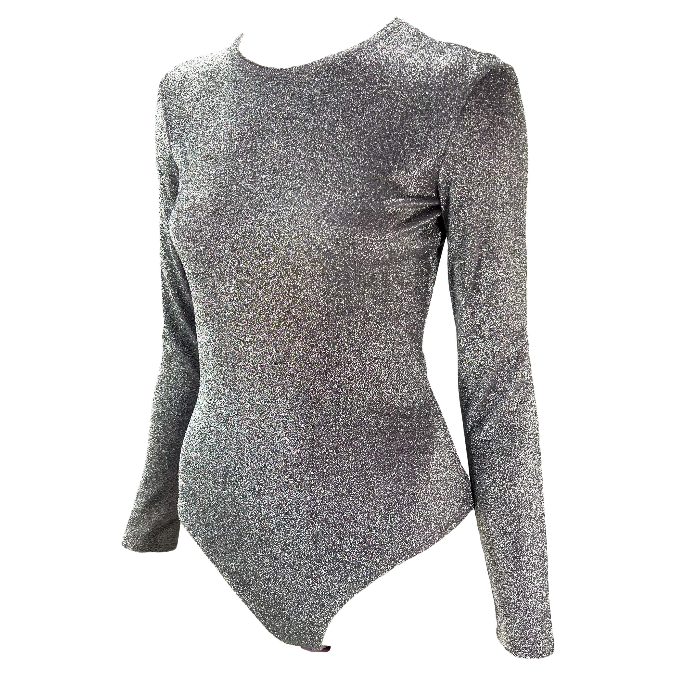 Con un lurex argento e pervinca, il body Gianni Versace Couture è stato disegnato da Gianni Versace. Dalla collezione Primavera/Estate 1994, questo fantastico costume intero presenta maniche lunghe e un'ampia scollatura. Brilla e risplende in questo