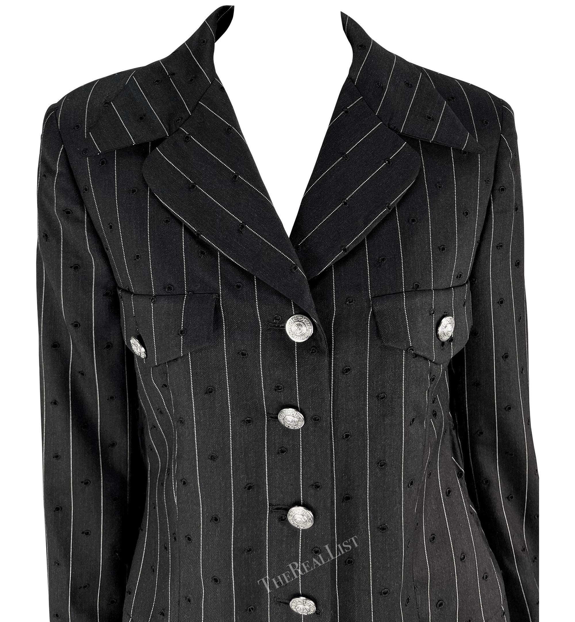 Questo blazer gessato traforato è della collezione Gianni Versace Couture Primavera/Estate 1994. Fabrice presenta linee nette e pulite in un tessuto traforato che richiama le influenze punk che hanno caratterizzato la collezione. I bottoni Medusa