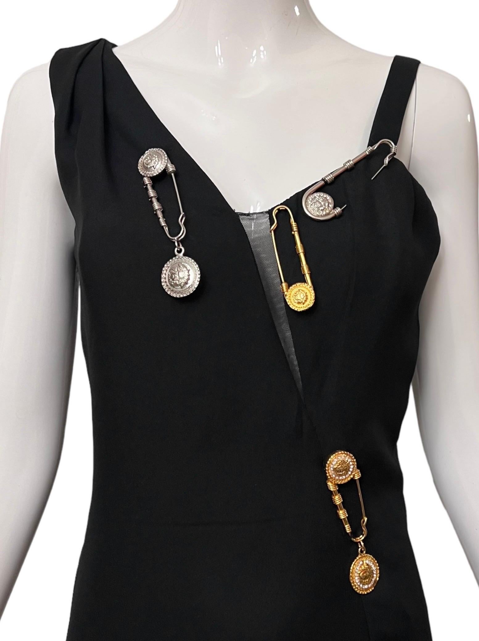 Stunning Gianni Versace vintage black safety pin mini dress from the iconic Spring Summer 1994 punk inspired collection.
The bodice of the dress is adorned with gold and silver Medusa metal safety pins, some are rhinestone encrusted. 
Side