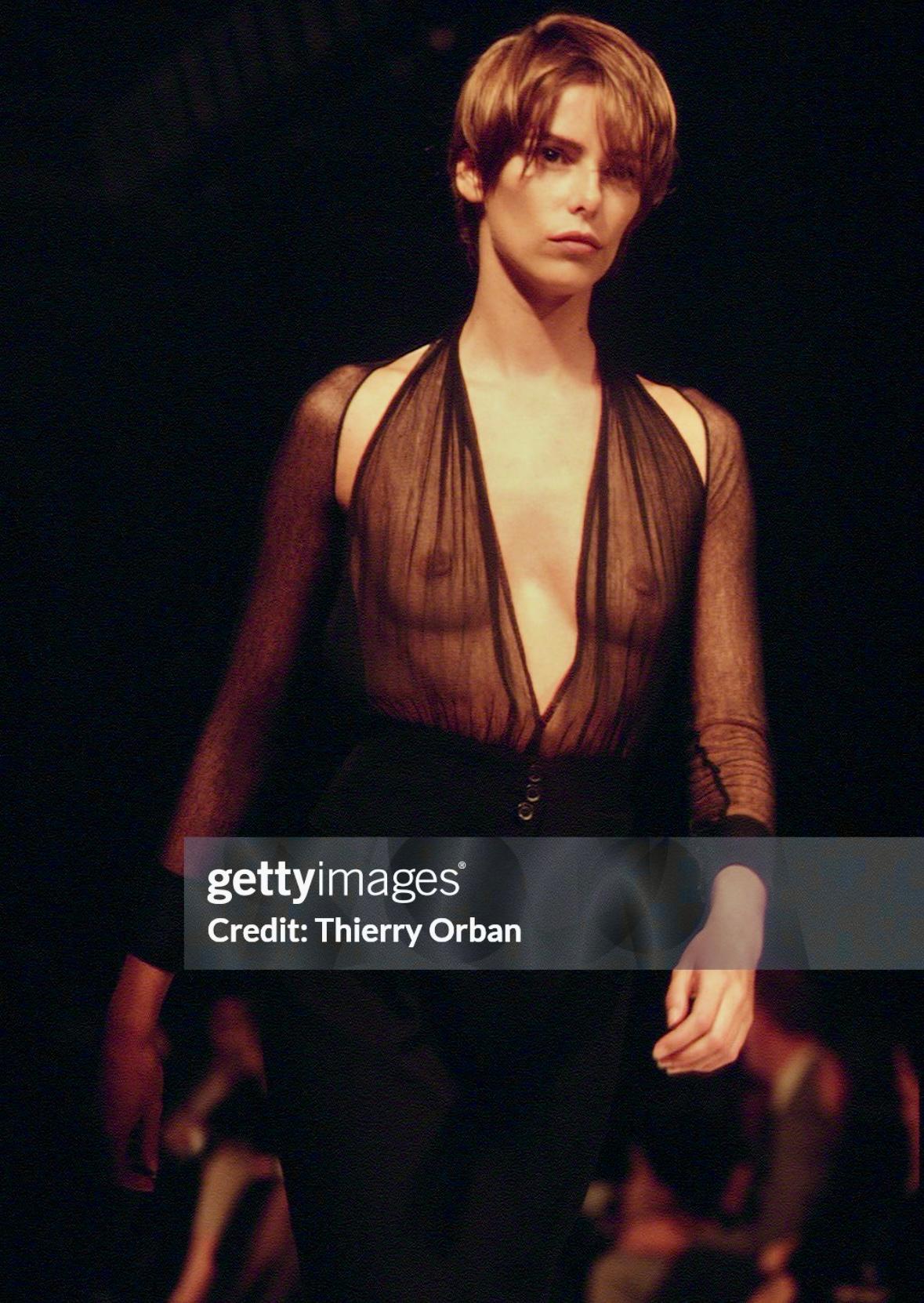 From the Spring/Summer 1995 collection, this ultra-sexy grey Ann Demulemeester top debuted on the season's runway. Featuring a plunging neckline and sheer bust, this vest-style top is made complete with an exposed back, halterneck tie, and button