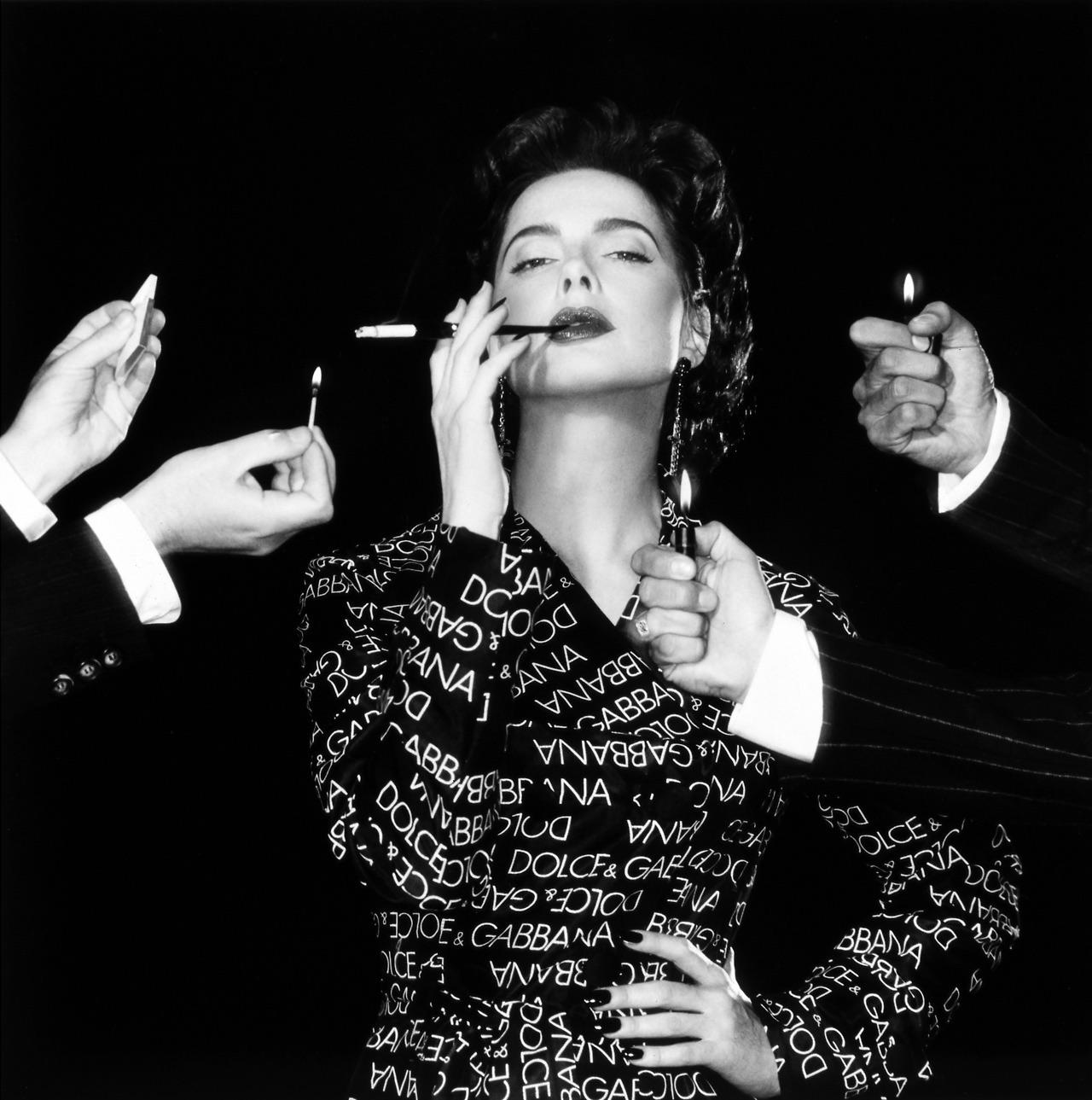 Questa minigonna di Dolce & Gabbana della collezione primavera/estate 1995 è realizzata in cotone nero e presenta un motivo a logo bianco a orientamento alternato. È disegnato con una vita alta e uno spacco laterale alto. La stampa del marchio ha
