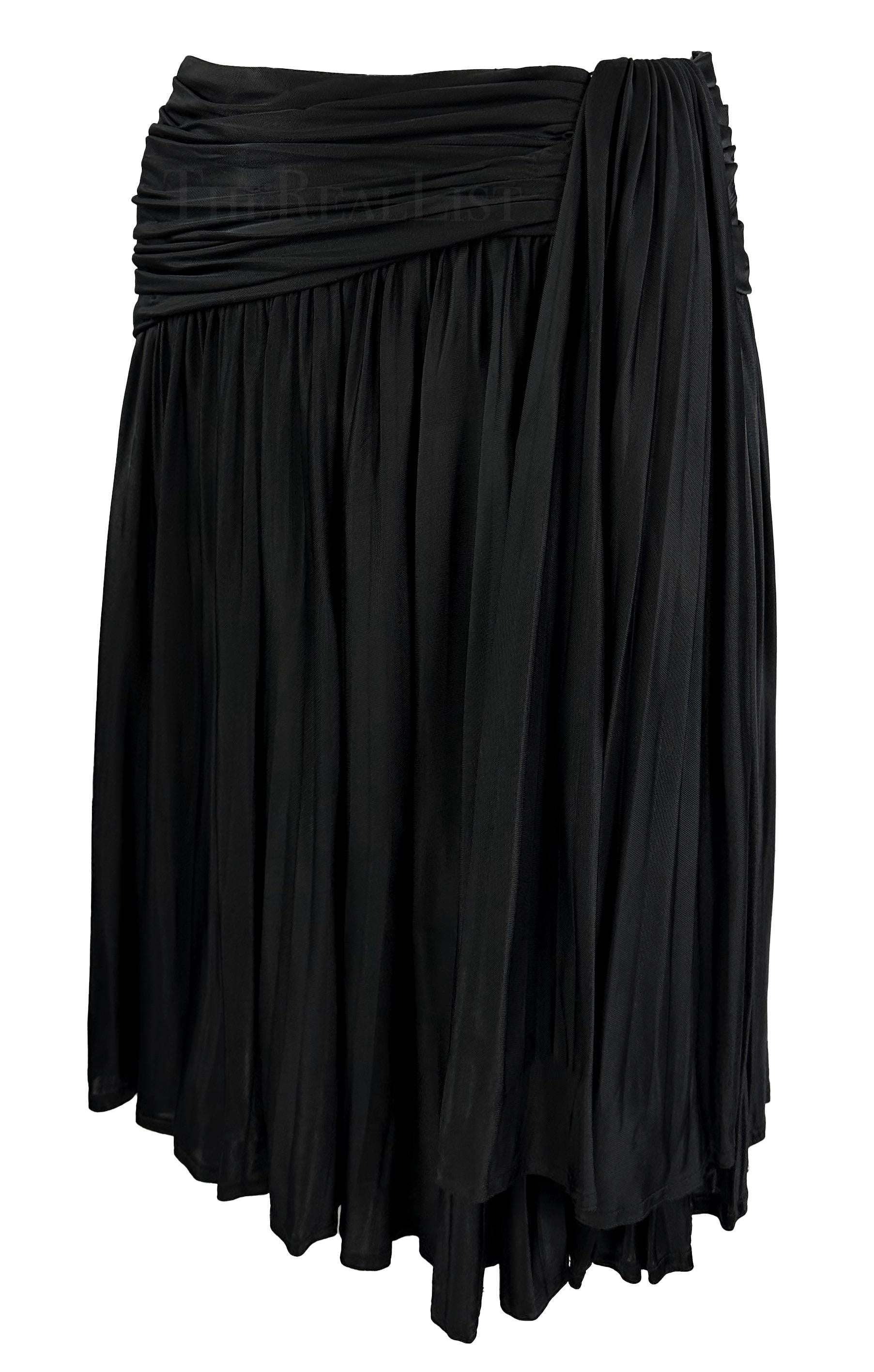 Dieser schwarze Faltenrock im Wickelstil von Gianni Versace wurde von Gianni Versace für seine Frühjahr/Sommer-Kollektion 1995 entworfen. Dieser Faltenrock mit Schlag ist mit einem asymmetrischen Wickelmuster in der Taille versehen. 

Ungefähre