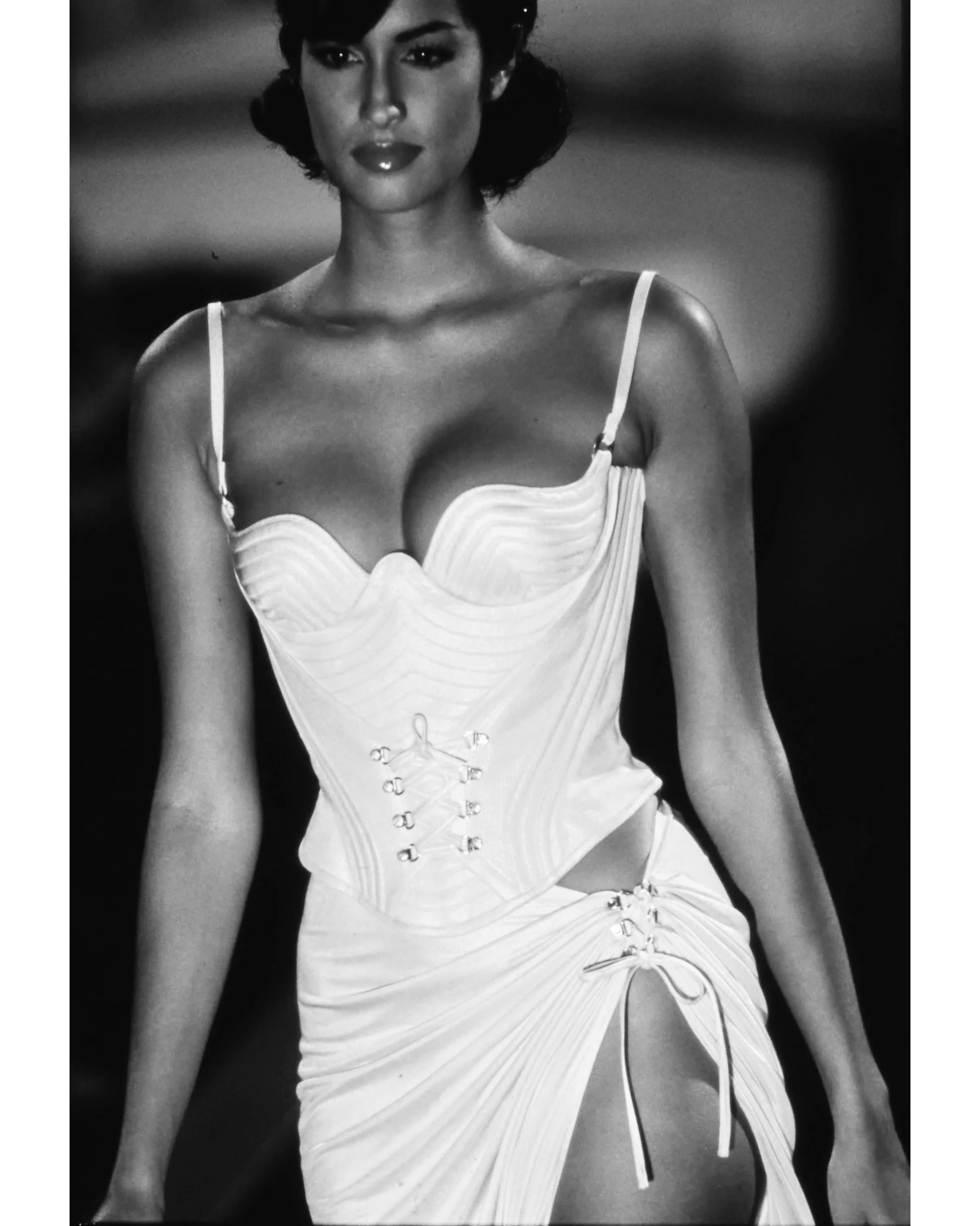 S/S 1995 Gianni Versace ecru lace-up corset top. Lace-up details at front waist and lace-up back with curved corset bodice, with gunmetal hardware. Sleeveless top with thin spaghetti straps. As seen on Yasmeen Ghauri on the runway (Look 74) in