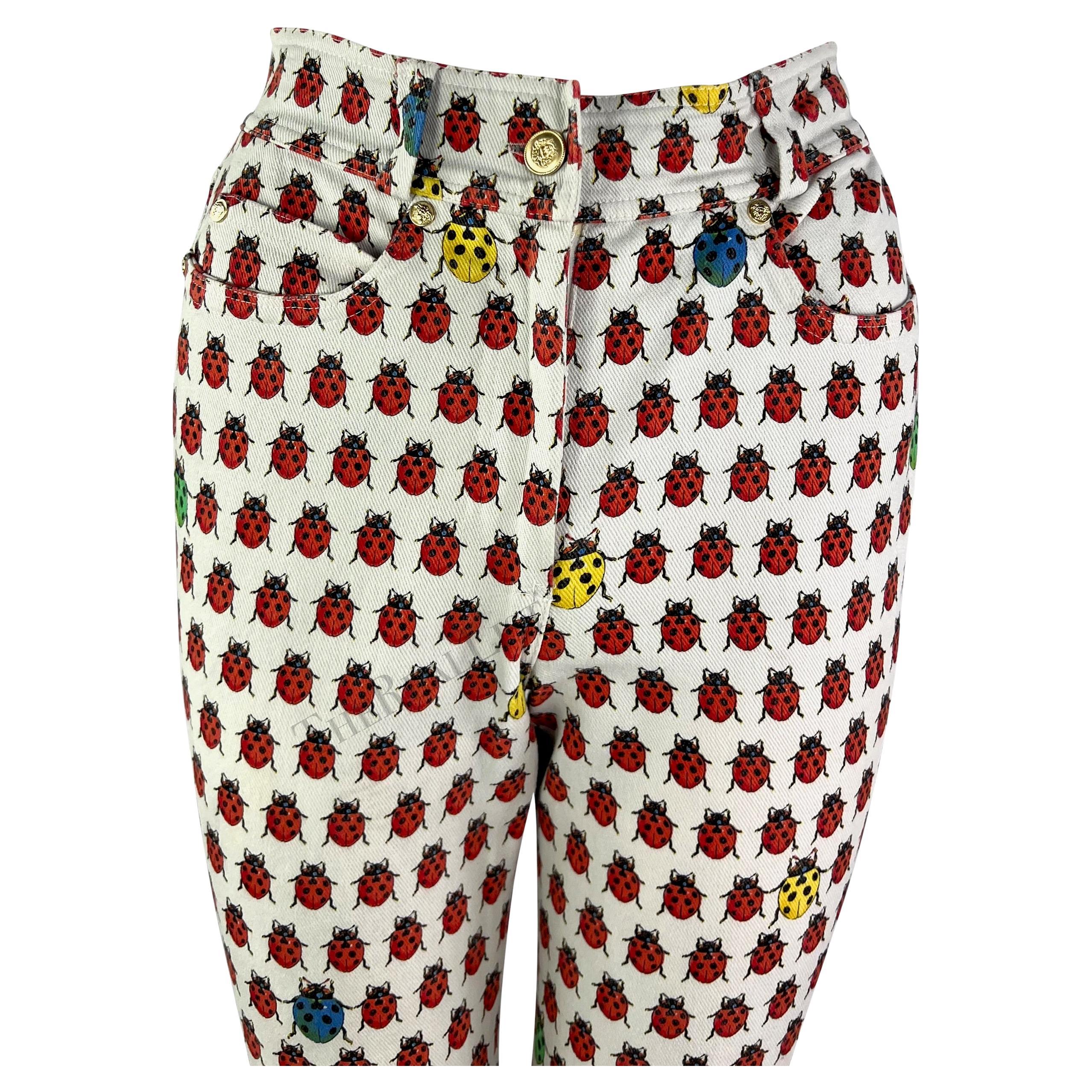 Presenting a pair of white ladybug print Gianni Versace jeans, designed by Gianni Versace. From the Spring/Summer 1995 collection, these high-waisted tapered pants are covered in multi-colored ladybugs, a print that first debuted on the season's