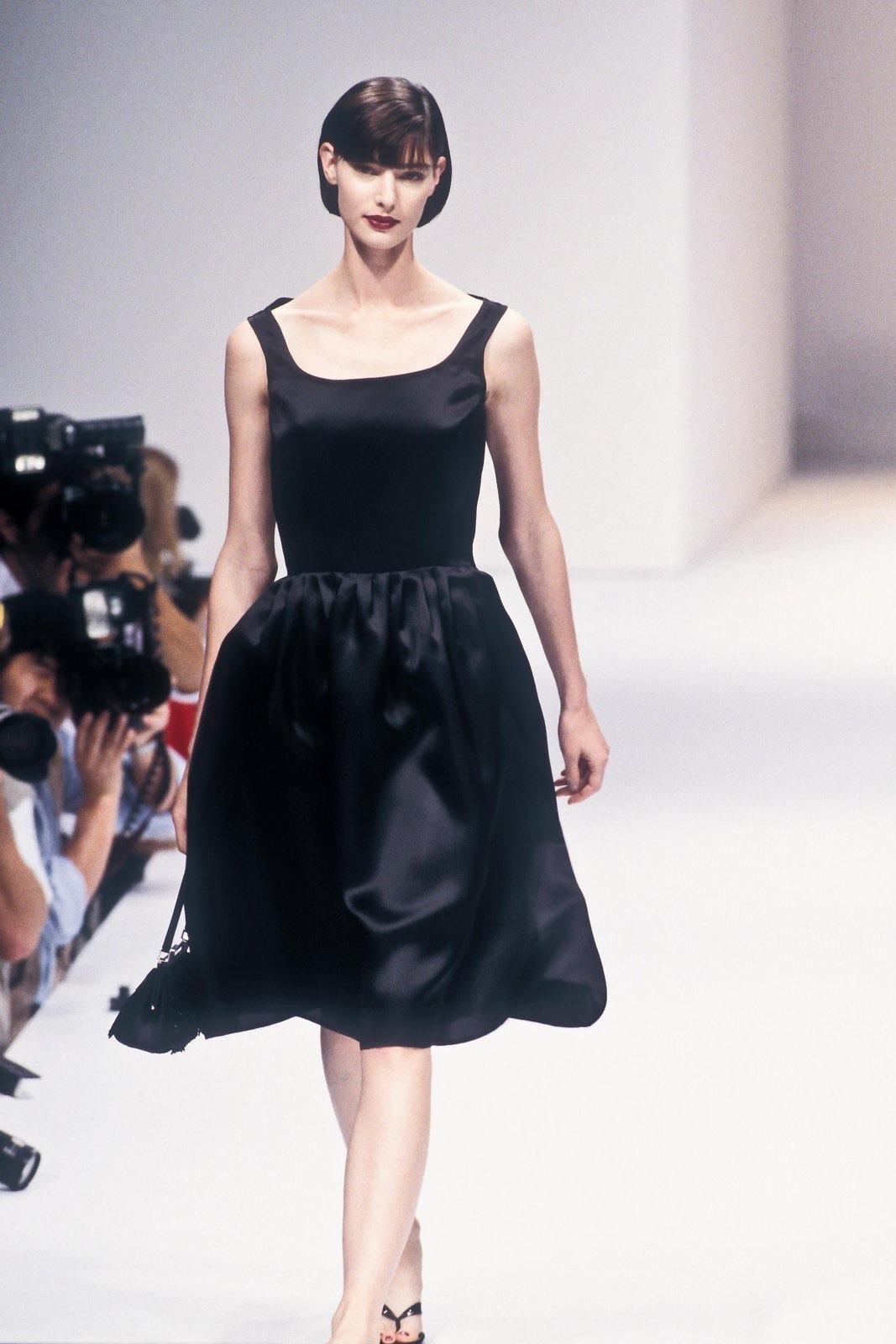 This black silk balloon-style skirt made its debut in Tom Ford's inaugural collection at Gucci, showcased in the Spring/Summer 1995 lineup. Crafted from a luxurious satin fabric, the skirt boasts gentle pleating at the waist, gracefully