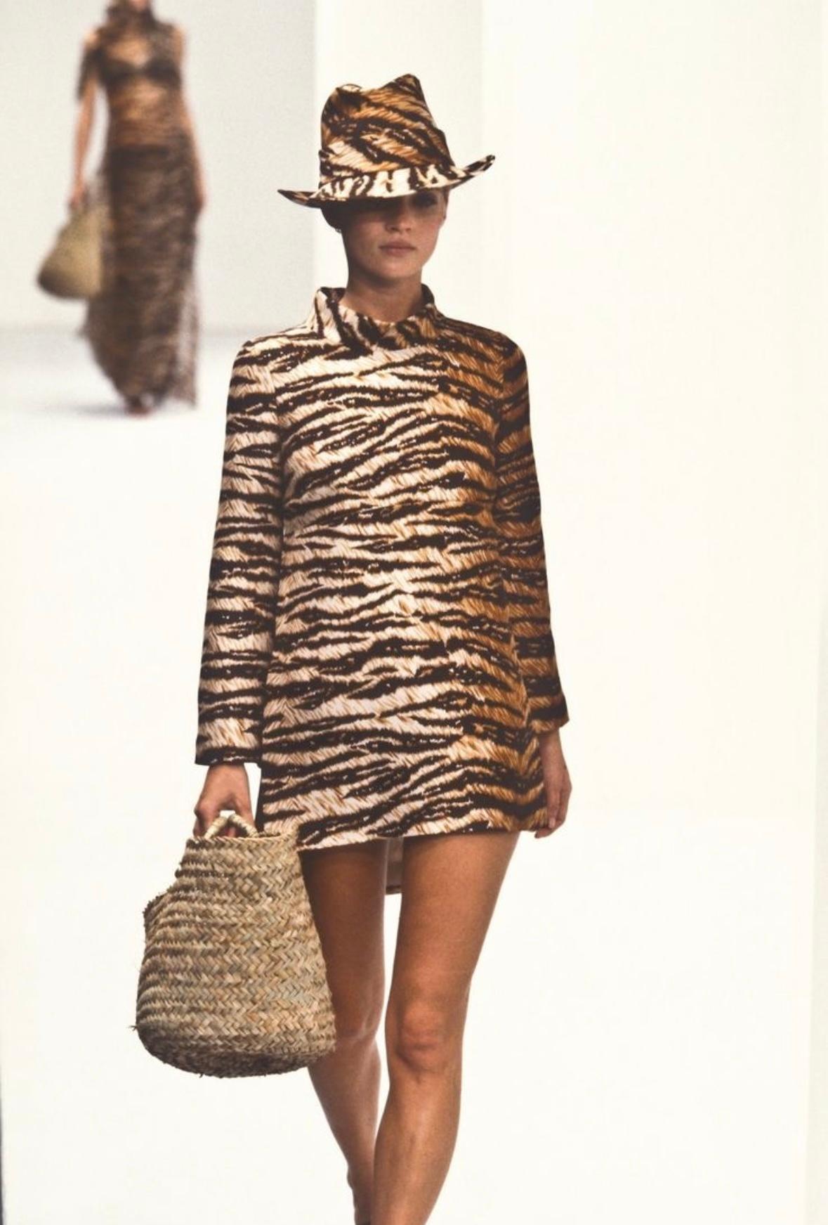 This Spring 1996 Dolce & Gabbana tunic top features a bold tiger print with a structured mock neckline and dramatic side slits. Worn by Kate Moss on the season's runway, this piece reflects the collection's inspiration—Monica Vitti's effortless