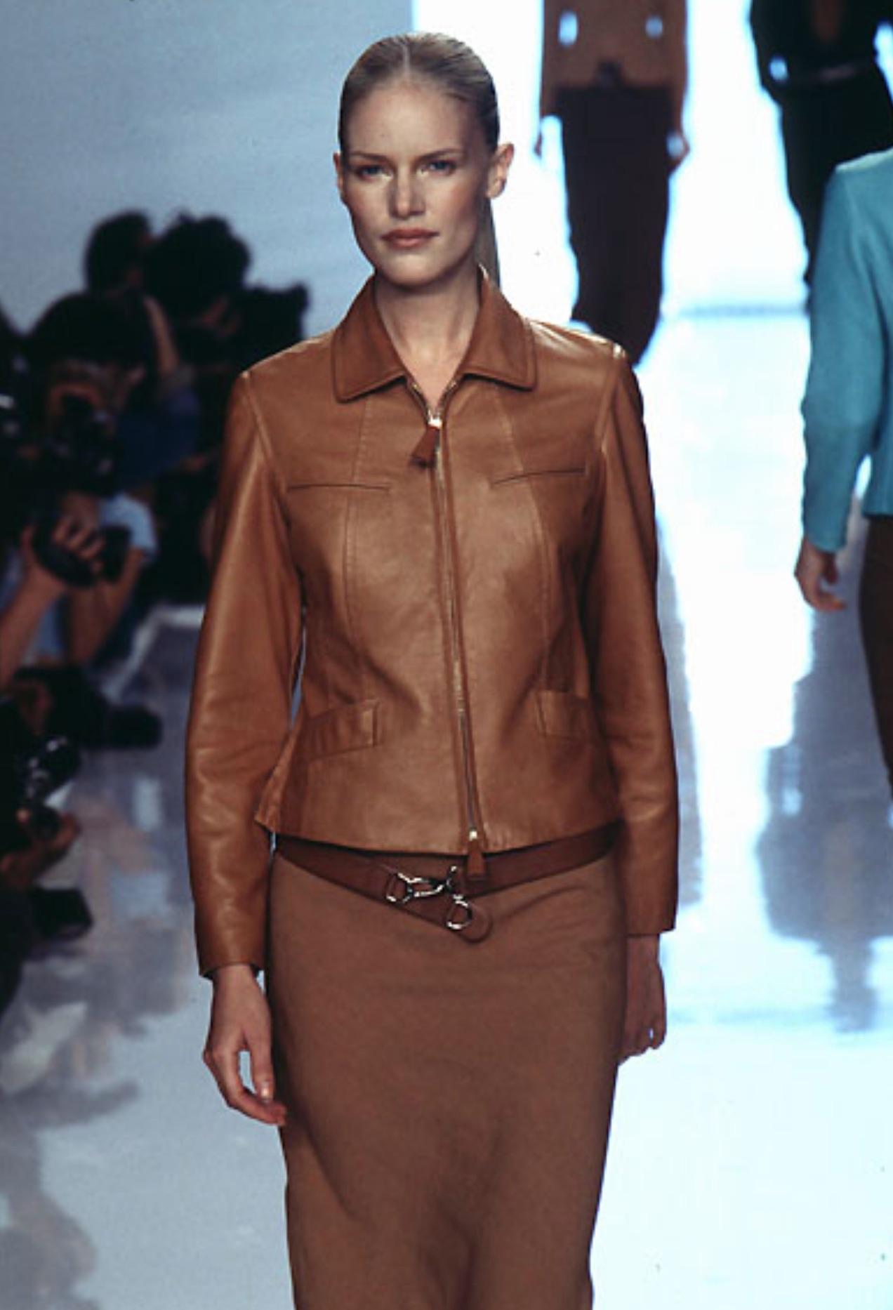 From Donna Karan’s Spring/Summer 1996 collection, this soft tan lambskin jacket features a sleek silhouette with a structured collar, horizontal chest zips, oversized leather pull tabs, and angled flap pockets. Debuting on the season's runway, this