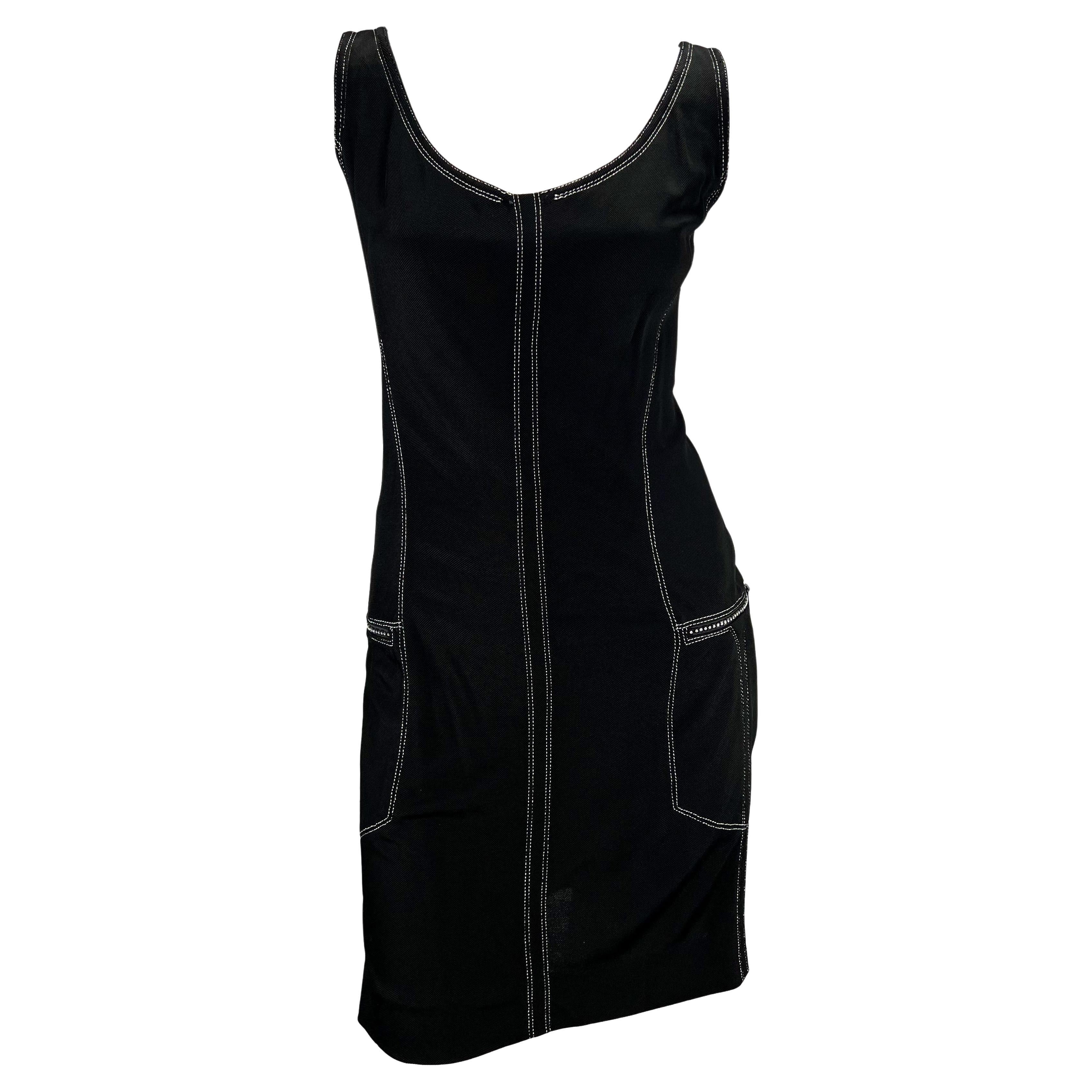 Présentation d'une robe noire sans manches Gianni Versace Couture, conçue par Gianni Versace. Issue de la collection printemps/été 1996, cette robe en tricot est ornée de coutures argentées et de poches zippées ornées de strass sur chaque hanche.