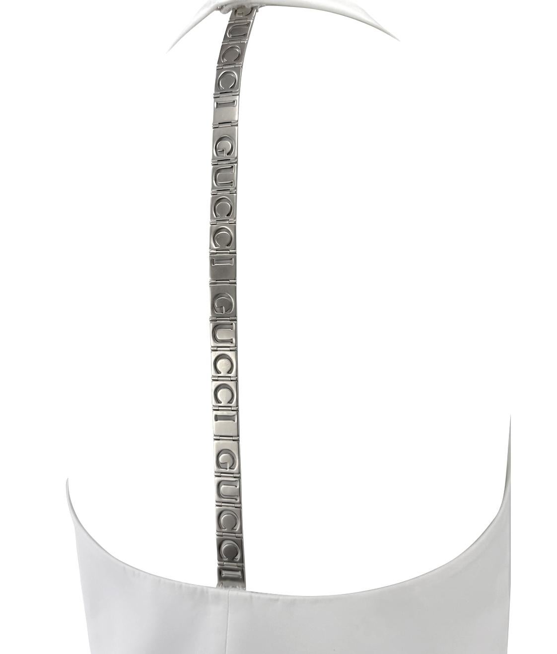 From Gucci’s Spring/Summer 1996 collection under Tom Ford, this white mini dress features a sleek halter neckline and an open back. The silhouette is anchored by a bold silver-tone spine strap adorned with repeating Gucci logo cutout, delivering a