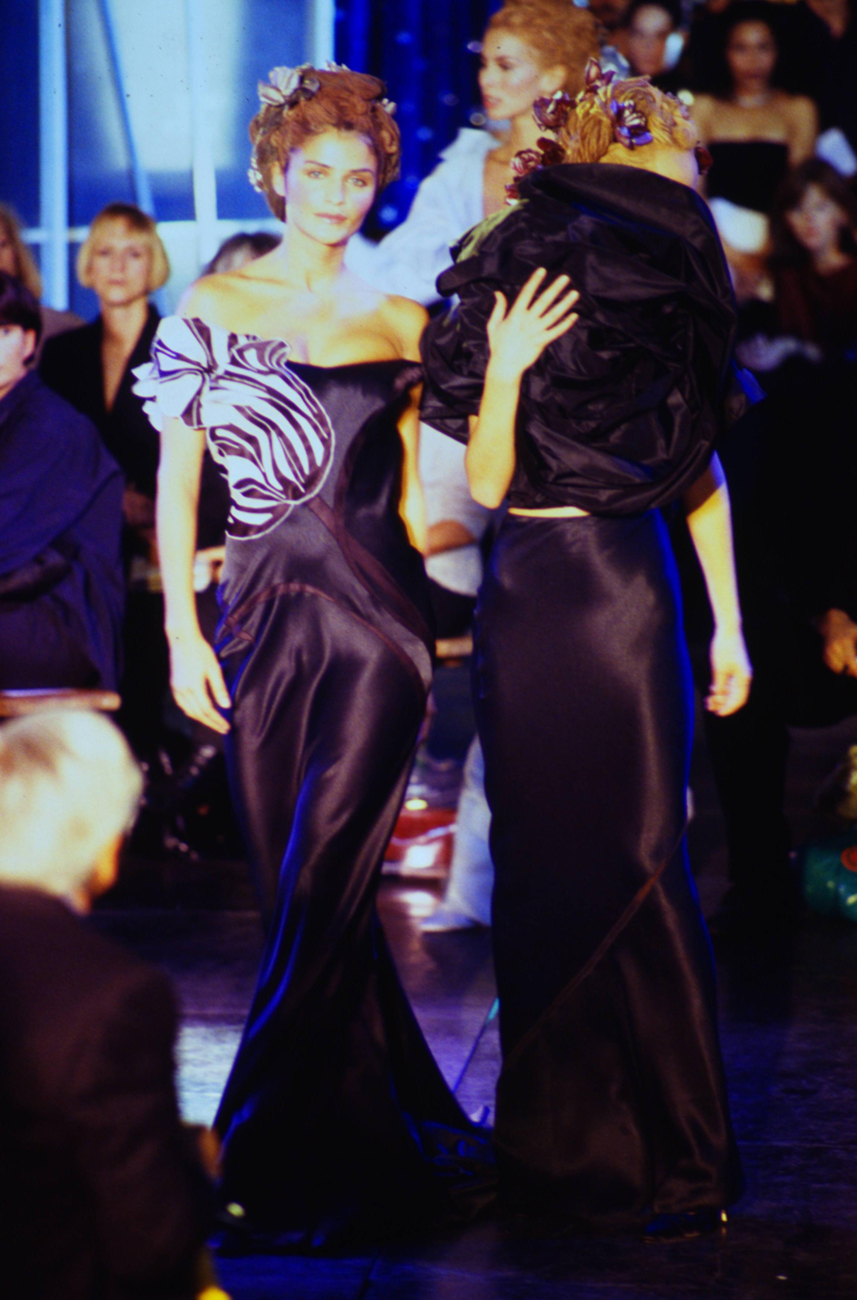 S/S 1996 John Galliano black and white sculptural sleeve gown with train. Off-shoulder gown with long, full train. Black and white geometric sleeve and bust asymmetrical detail, with subtle flower motif. Deep purple curved contrasting paneling