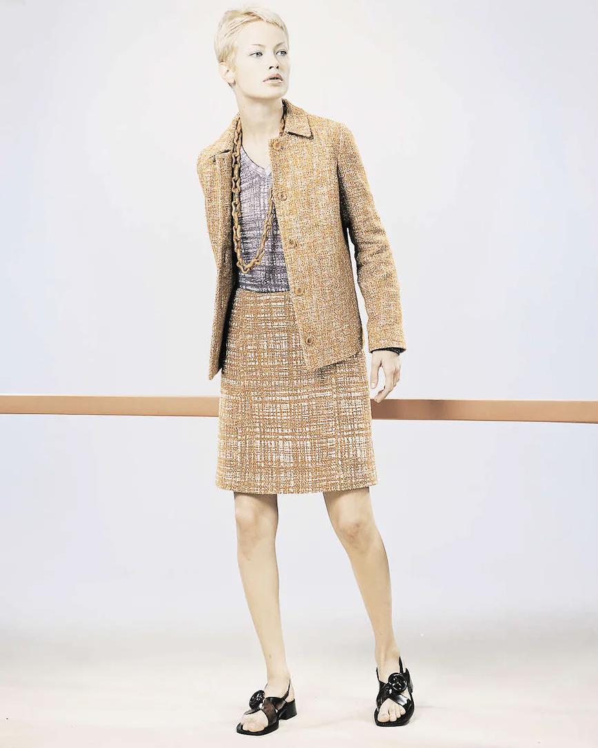 S/S 1996 Prada by Miuccia Prada orange 'ugly chic' tweed skirt set. Collared tweed blazer jacket with four tortoiseshell brown front button closures pairs with matching tweed mini wrap skirt with concealed button closure. Features circular