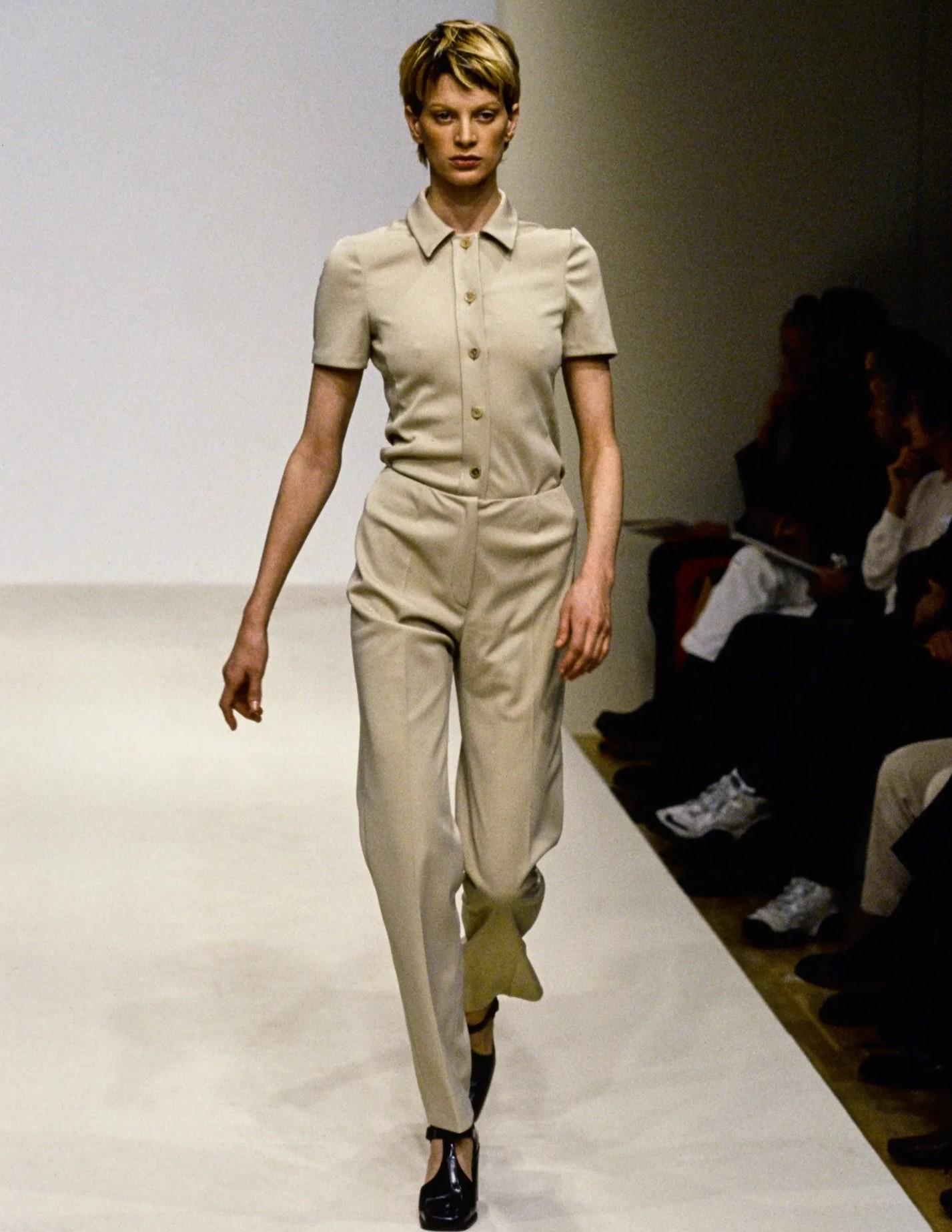 S/S 1996 Prada by Miuccia Prada tan short sleeve pant suit set. Button-up tan shirt and mid-rise straight leg pant set. Buttons are matching tan with subtle tortoiseshell throughout. Fabric Contents are 100% Polyester. As seen on the runway on