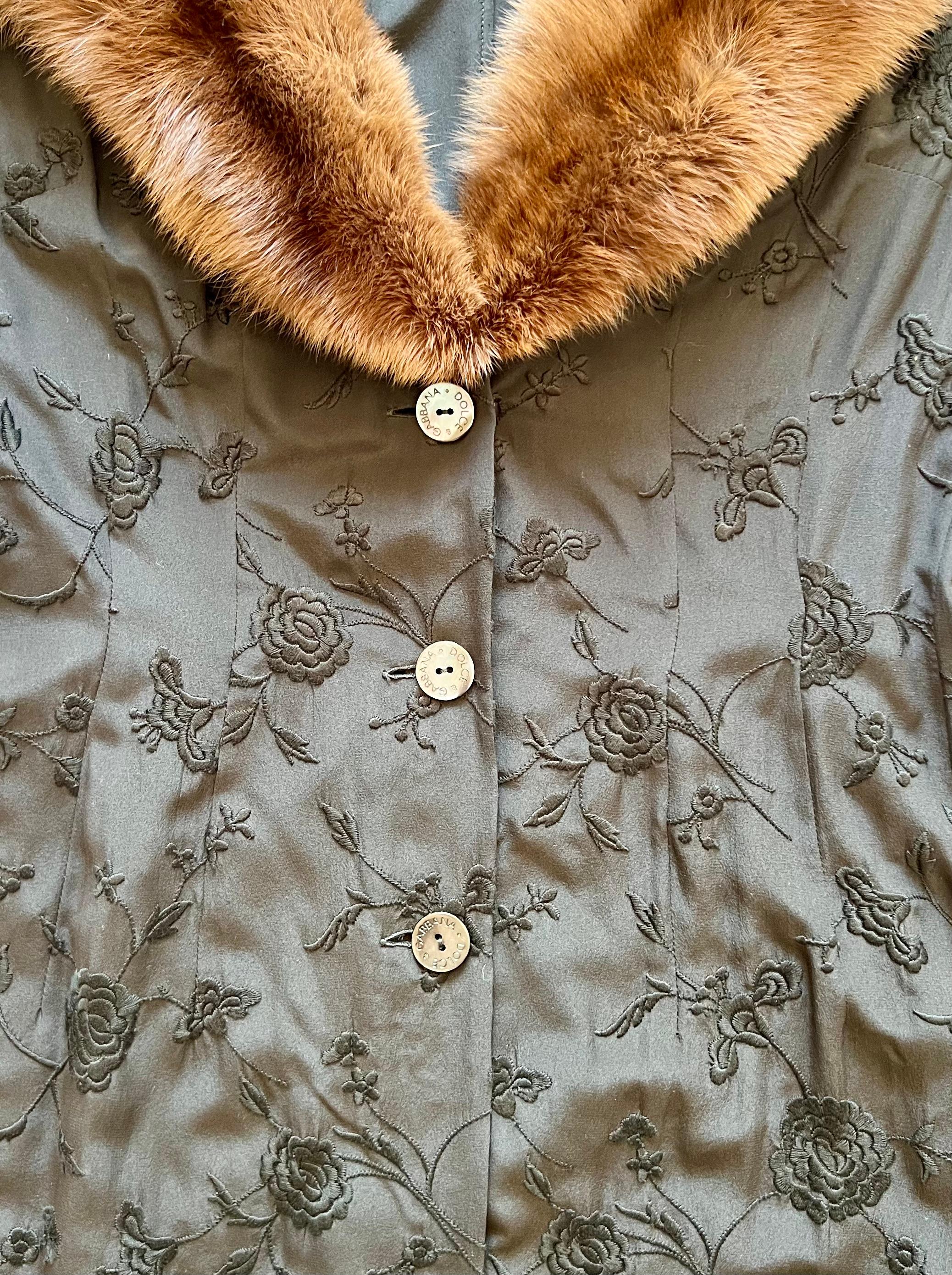 This Spring/Summer 1997 Dolce & Gabbana coat dress is crafted from black silk with elaborate floral embroidery. The coat features a dramatic sable mink fur shawl collar. It is designed with a single-breasted button closure, accentuated by large