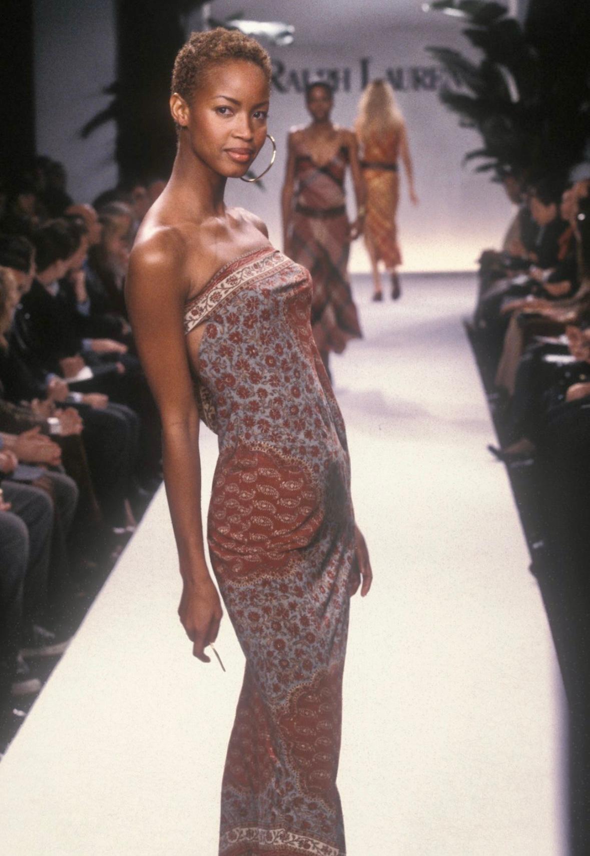 From the Spring/Summer 1997 collection, this floral print Ralph Lauren dress debuted on the season's runway, modeled by Georgianna Robertson. Covered in a rust and pale blue floral print, this strapless gown clings to the body. Effortless, this