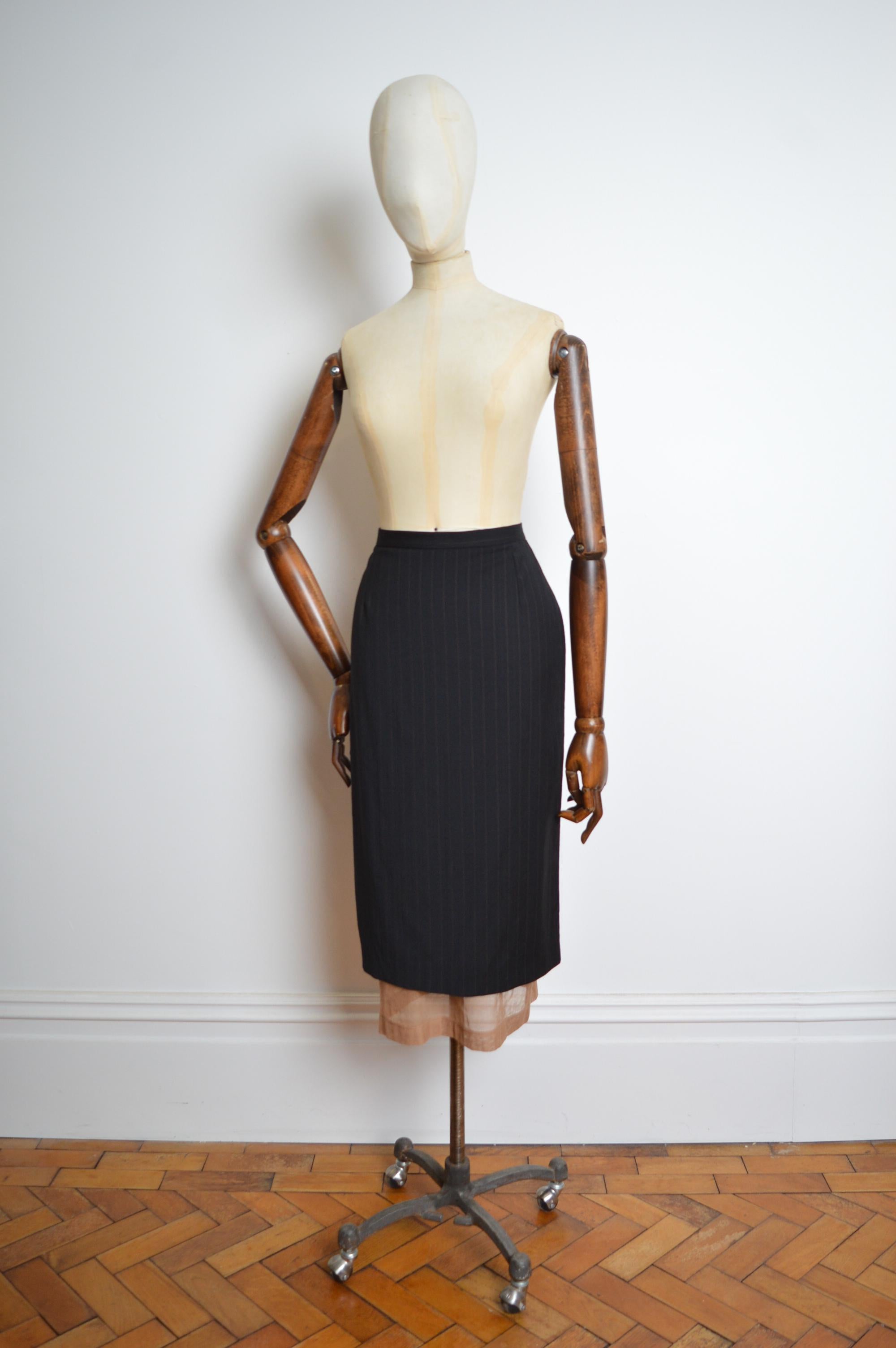 Primavera / Verano 1998 Dolce & Gabbana Falda lápiz larga a rayas negra con detalle de malla bajo capa.
Silueta de talle alto, tejido a rayas negras y marrones con una capa interior de malla en color nude. Cierre de gancho de herrador en la espalda