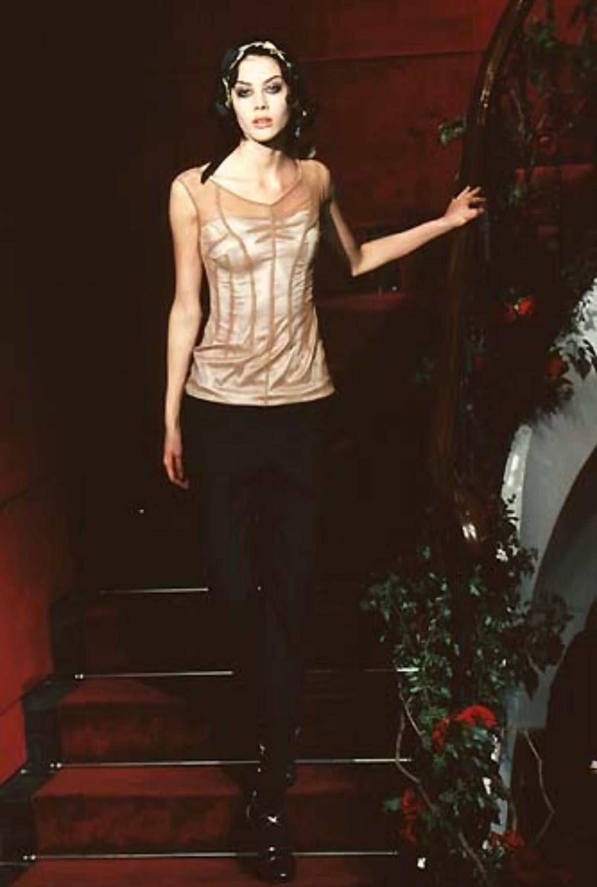 Issue de la collection Printemps/Été 1998, cette robe se compose d'une base en satin argenté et d'un extérieur en maille transparente taupe. La couche intérieure argentée du bustier est visible à travers la maille, ce qui donne à cette robe une