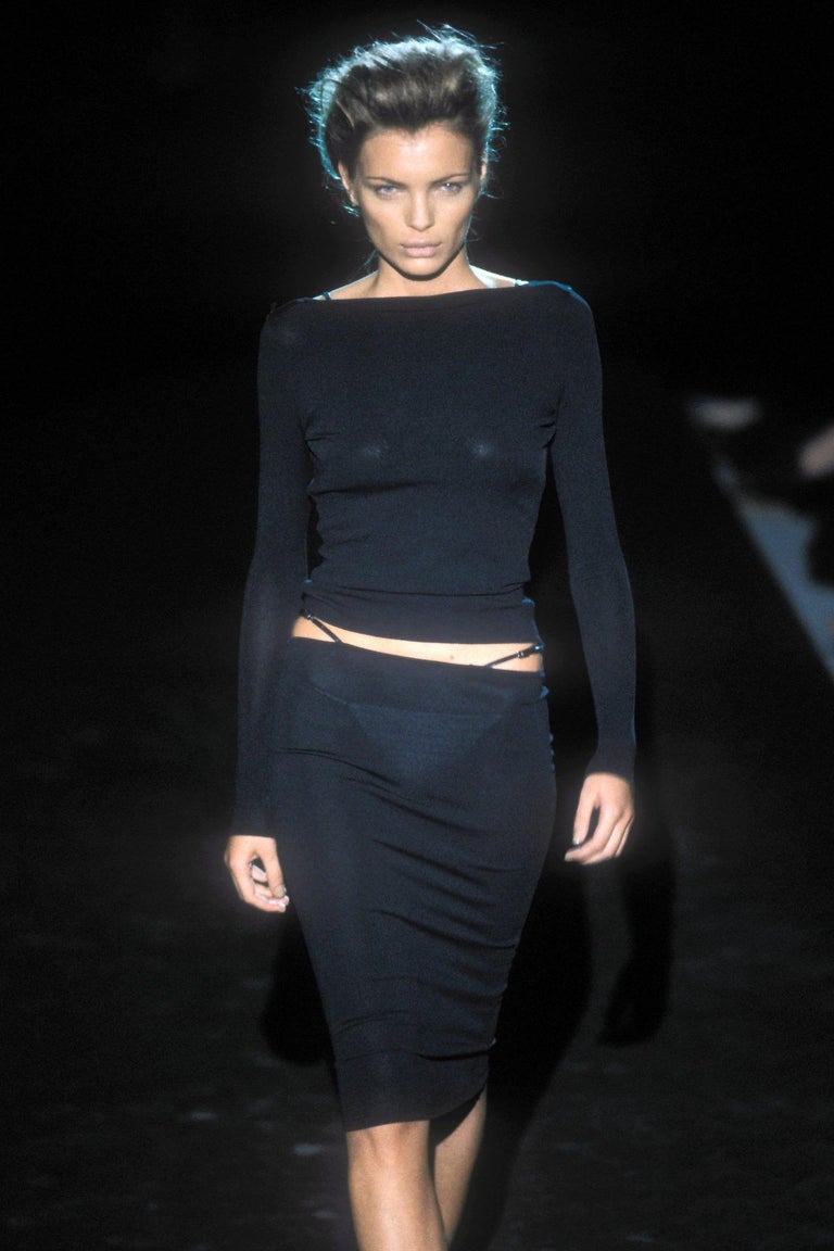 TheRealList presents: a figure-hugging little black dress designed by Tom Ford for Gucci's Spring/Summer 1998 collection. This piece features the iconic 'G' buckle leather straps that were heavily featured in the runway presentation at the hips. We