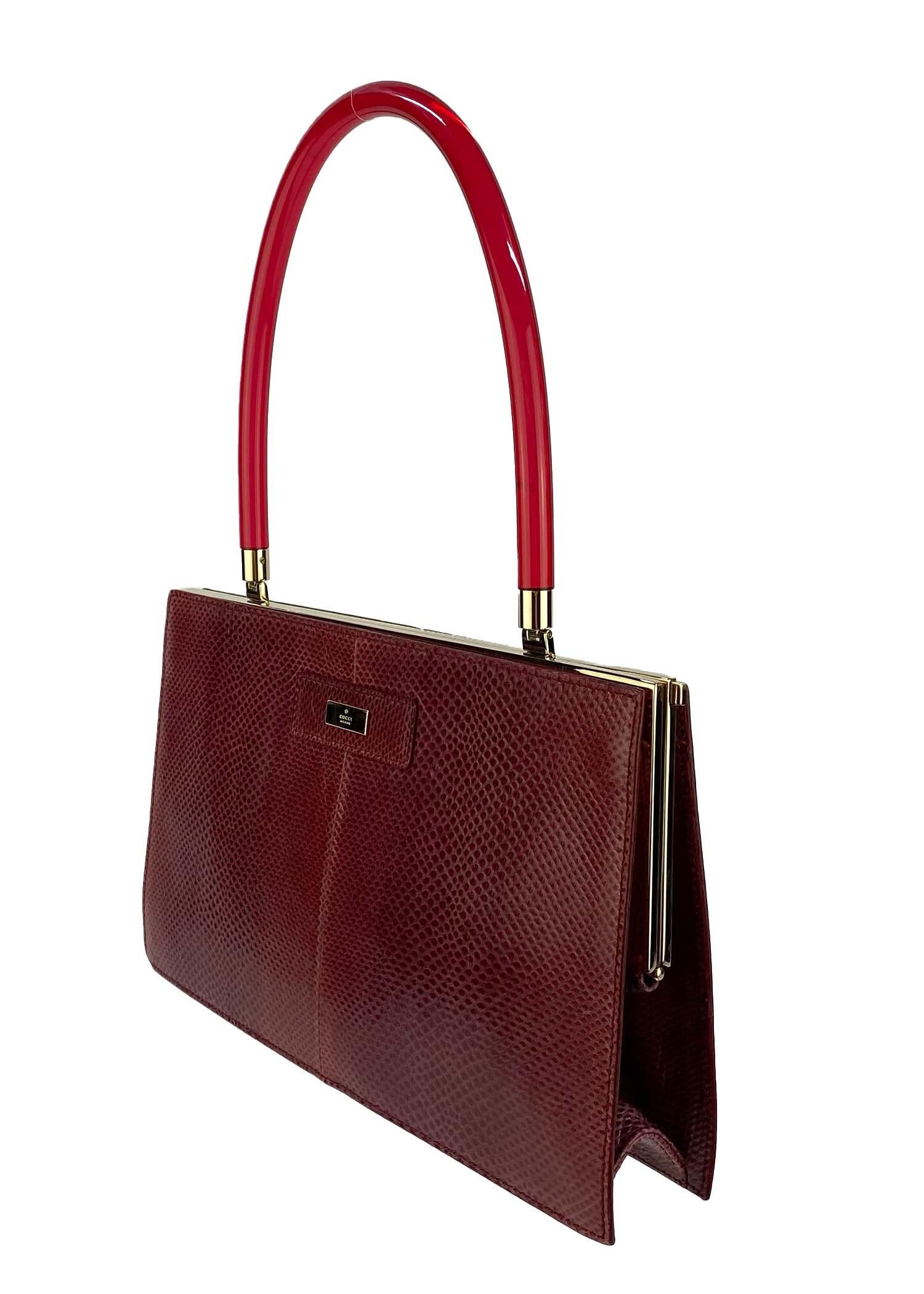 Presenting a rare deep red lizard skin Gucci bag, designed by Tom Ford. This beautiful bag is constructed primarily of red dyed Karung snake skin and is made complete with gold-colored accents and a clear red lucite handle. This bag, from the