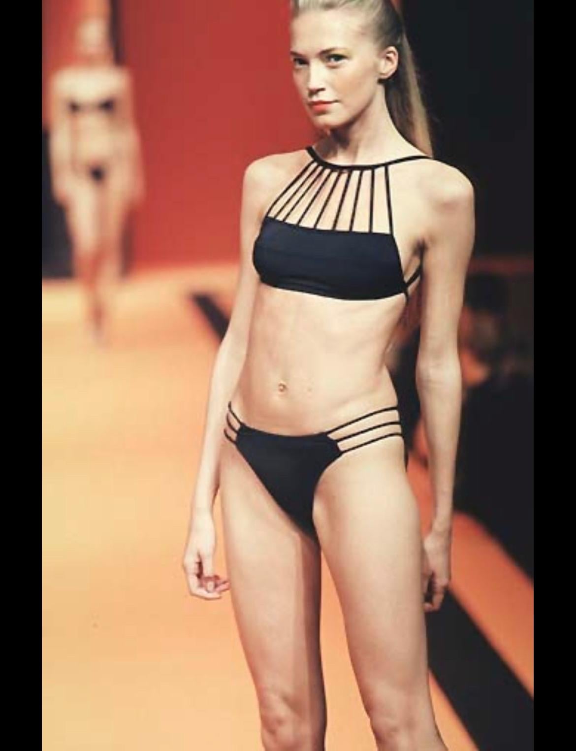 Presenting a fabulous black Herve Leger one-piece swimsuit. From the Spring/Summer 1998 collection, similar bathing suits were featured on the season's runway. This chic one-piece/bodysuit features a strap design above the bust and is made complete