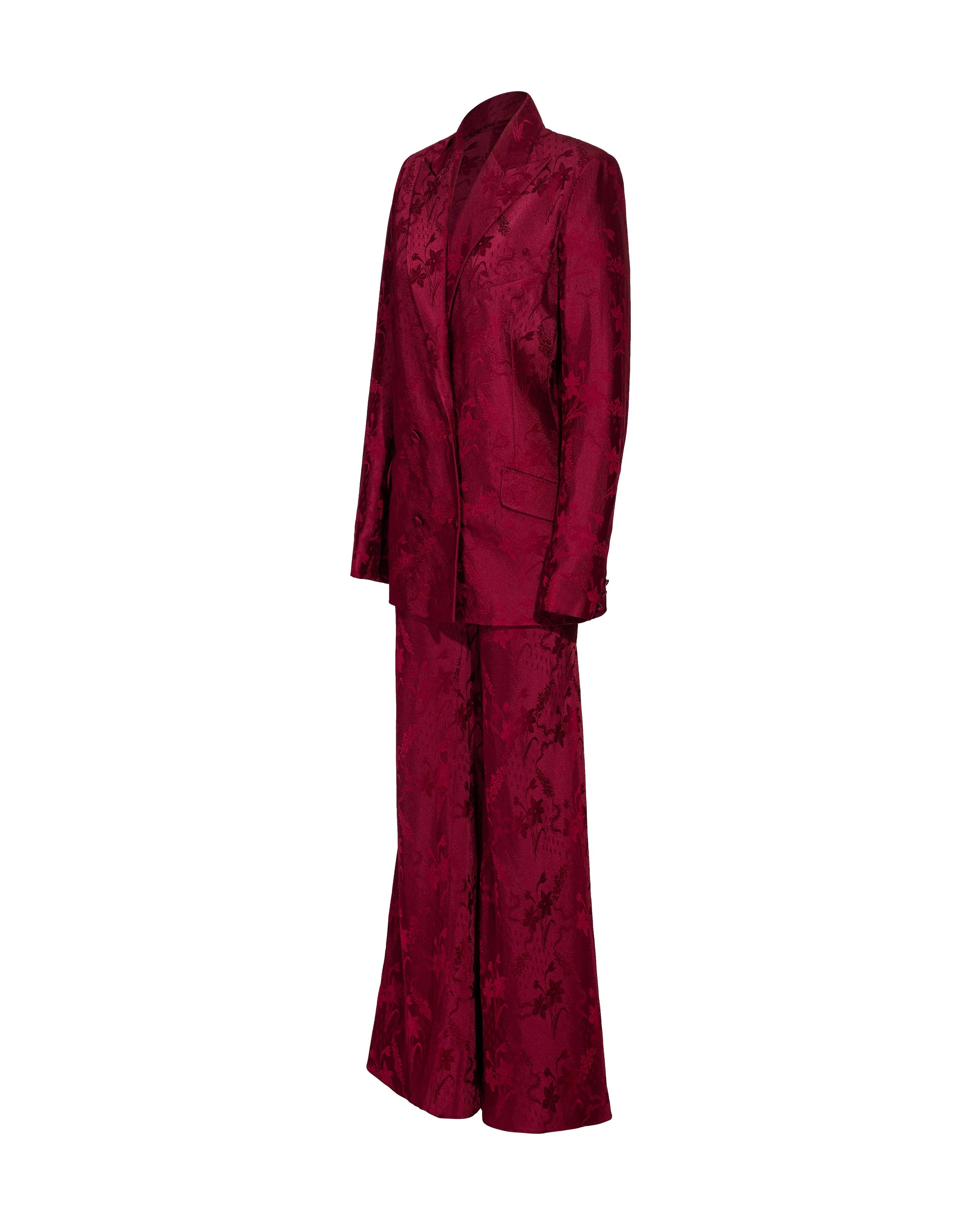 S/S 1998 John Galliano deep red floral pattern pant suit set. Deep red double-breasted blazer with notched lapels, floral motif pattern throughout and functional side flap pockets. Fully lined with bright fuchsia silk lining. Slight built-in